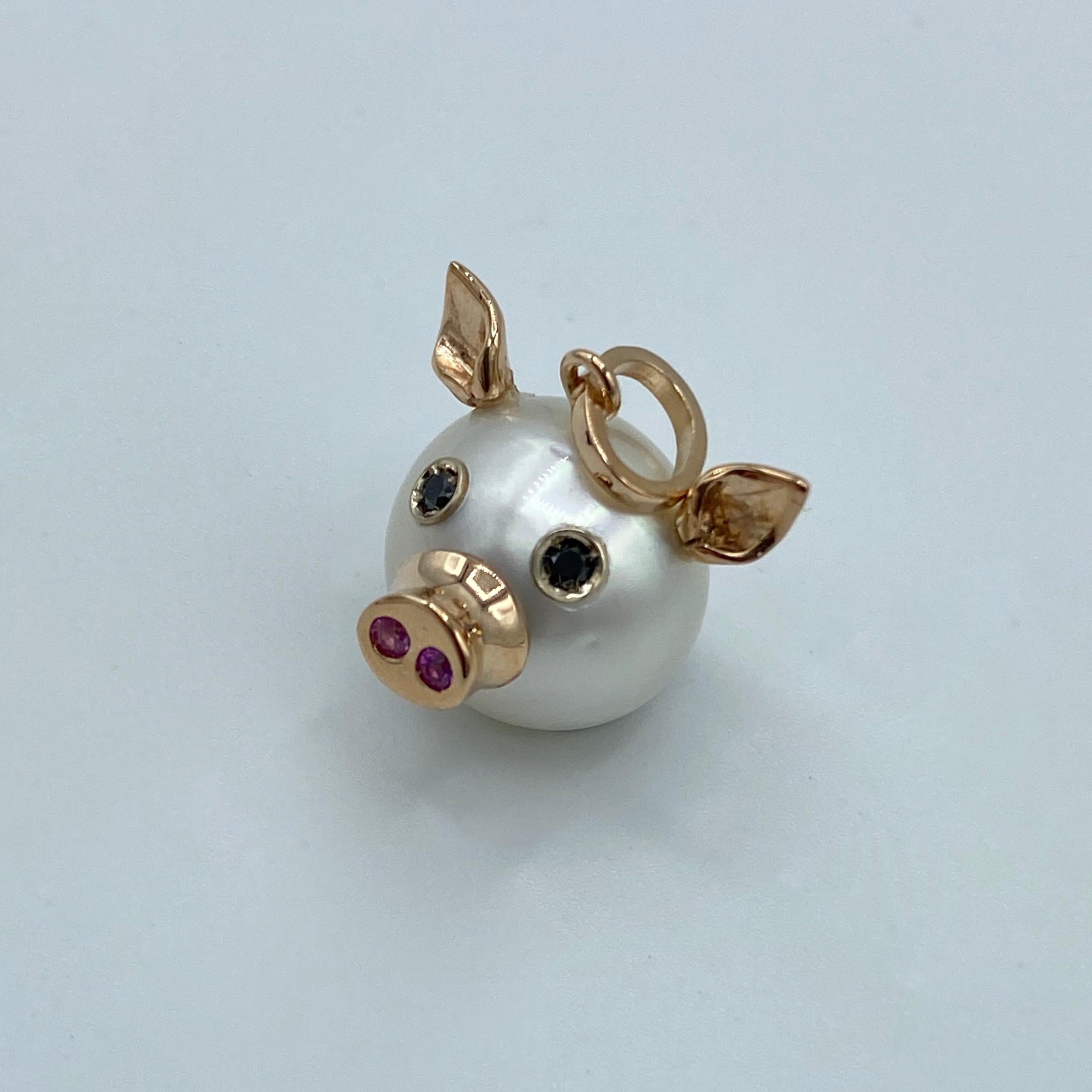 This nice pendant is made with a button Australian pearl. 
It has two ears, two eyes with black diamonds.  
In the holes of its nose there are two pink sapphires encrusted, in total ct 0.03.
All the particulars made in red gold excluding eyes.
The