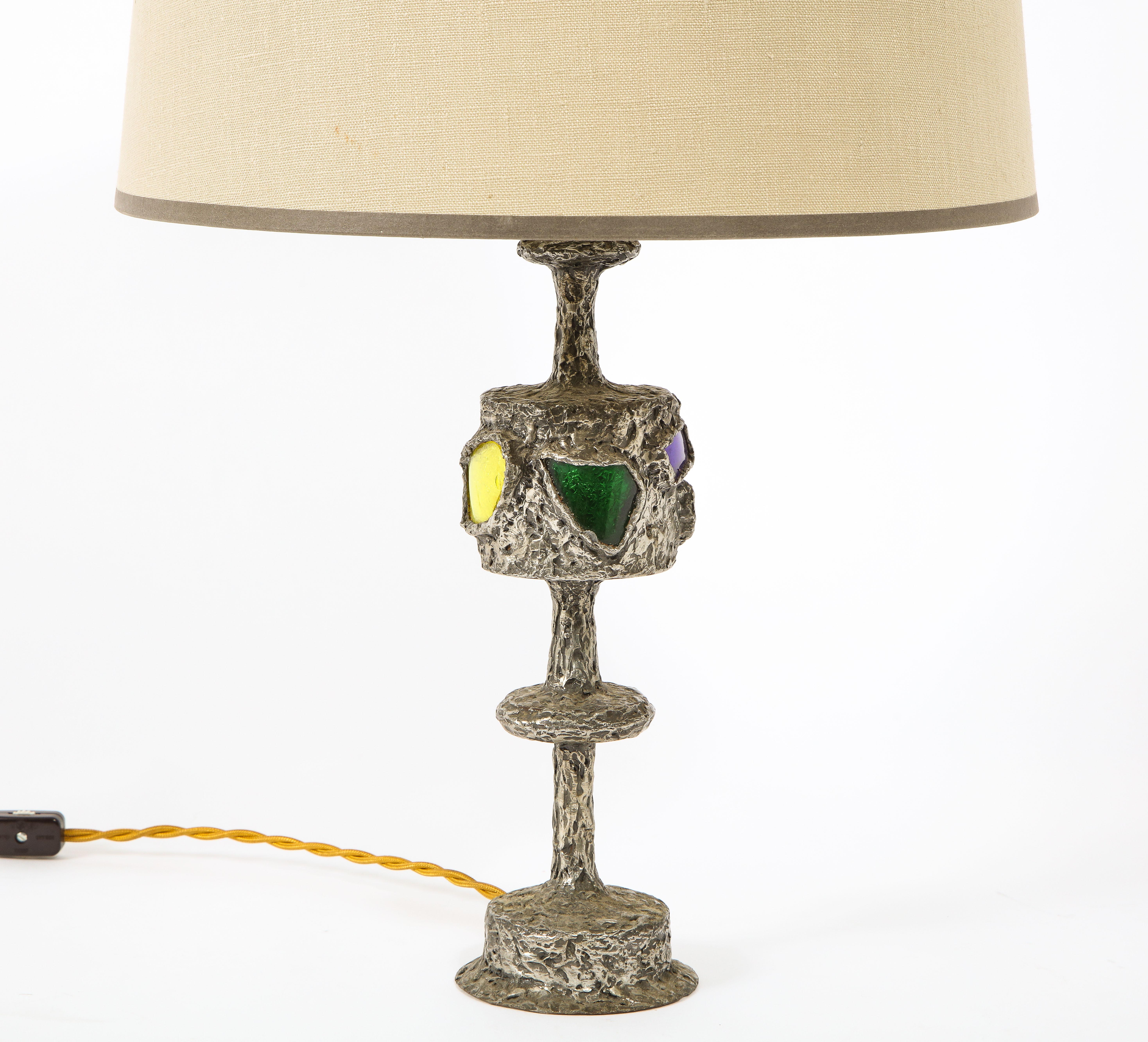 Merveilleuse lampe d'atelier en étain et verre d'art coloré de Raymond Trameau. En utilisant la technique du goutte-à-goutte, il donne l'impression de faire fondre du métal.

L'abat-jour n'est pas inclus.