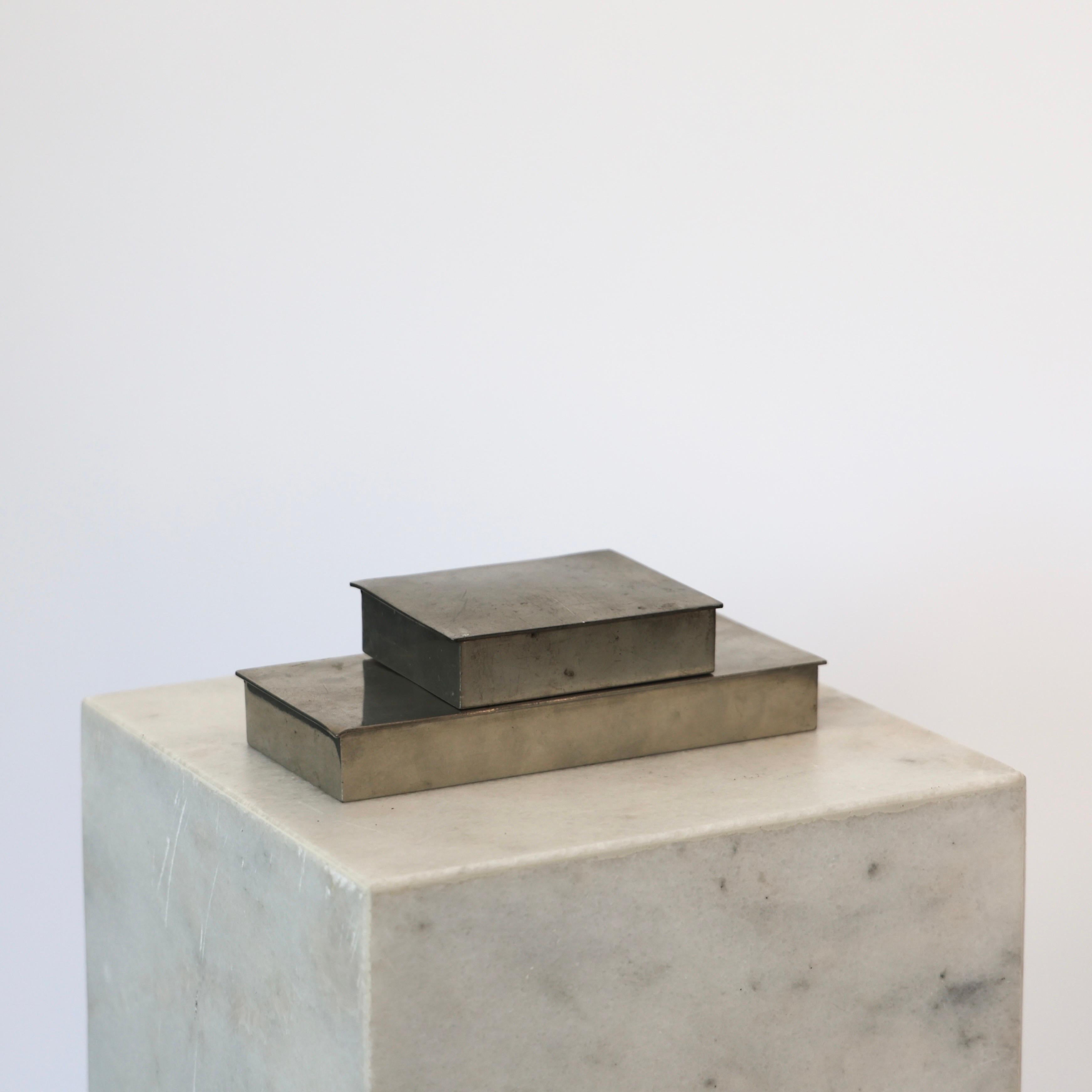 Elegant set of Pewter Boxes designed by Arne Erkers for Just Andersen in the 1950s. 

* Two (2) lidded boxes in pewter with wooden inner boxes. Originally cigarette boxes.
* Designer: Arne Erkers
* Style: 2494 and 2611
* Manufacturer: Just