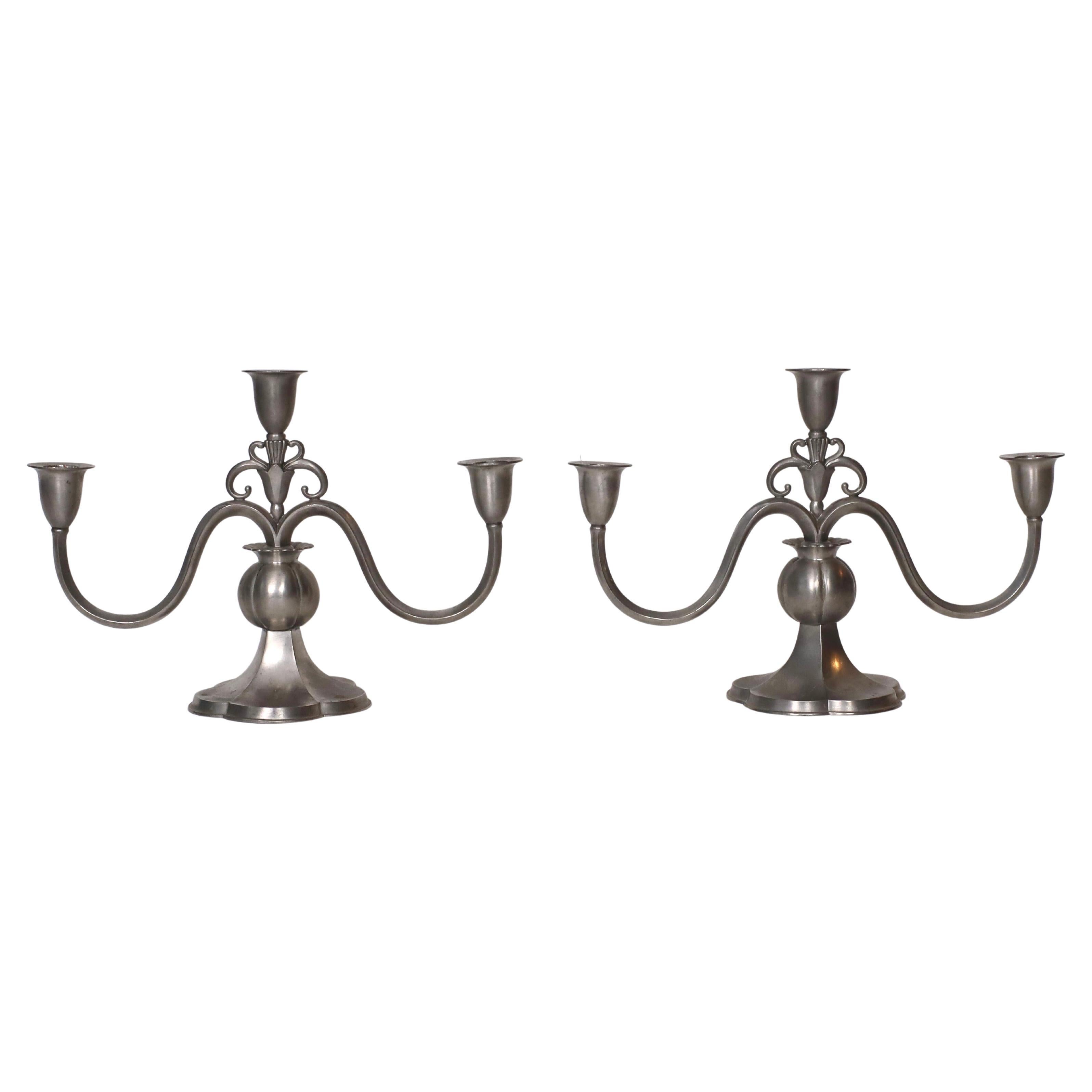 Ensemble de chandeliers en étain fabriqués par Just Andersen dans les années 1920. Un ensemble élégant pour une belle table. 

* Paire de bougeoirs en étain pour trois bougies 
* Fabricant : Just Andersen
* Style : 1169
* Année : 1918-1929
*