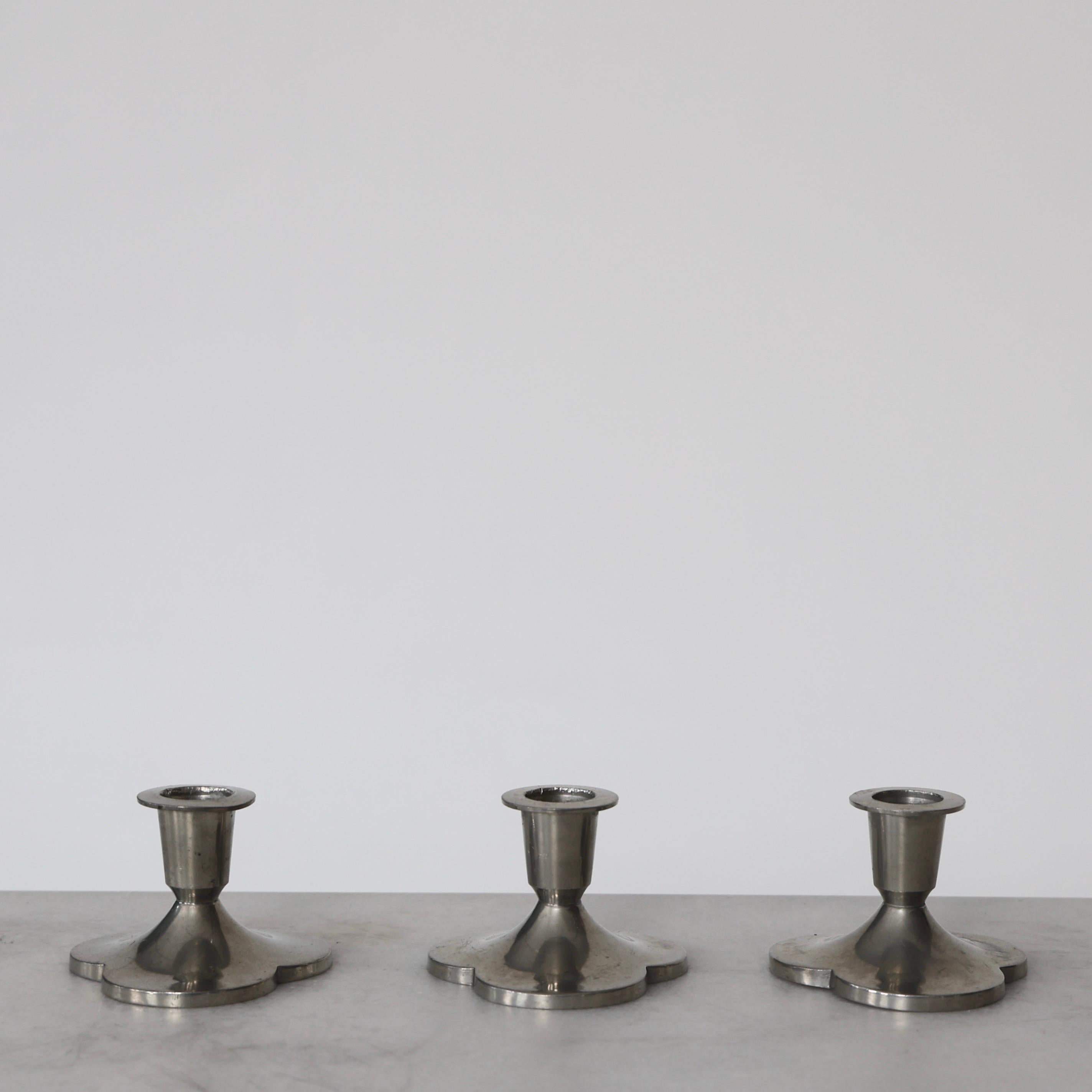 Set (3) of Clover-shaped Pewter Candle Holders designed by Just Andersen in the 1920s. A fine trio for a beautiful place. 

* Trio of small clover-shaped pewter candlestick holders
* Designer: Just Andersen
* Manufacturer: Just Andersen
* Style: