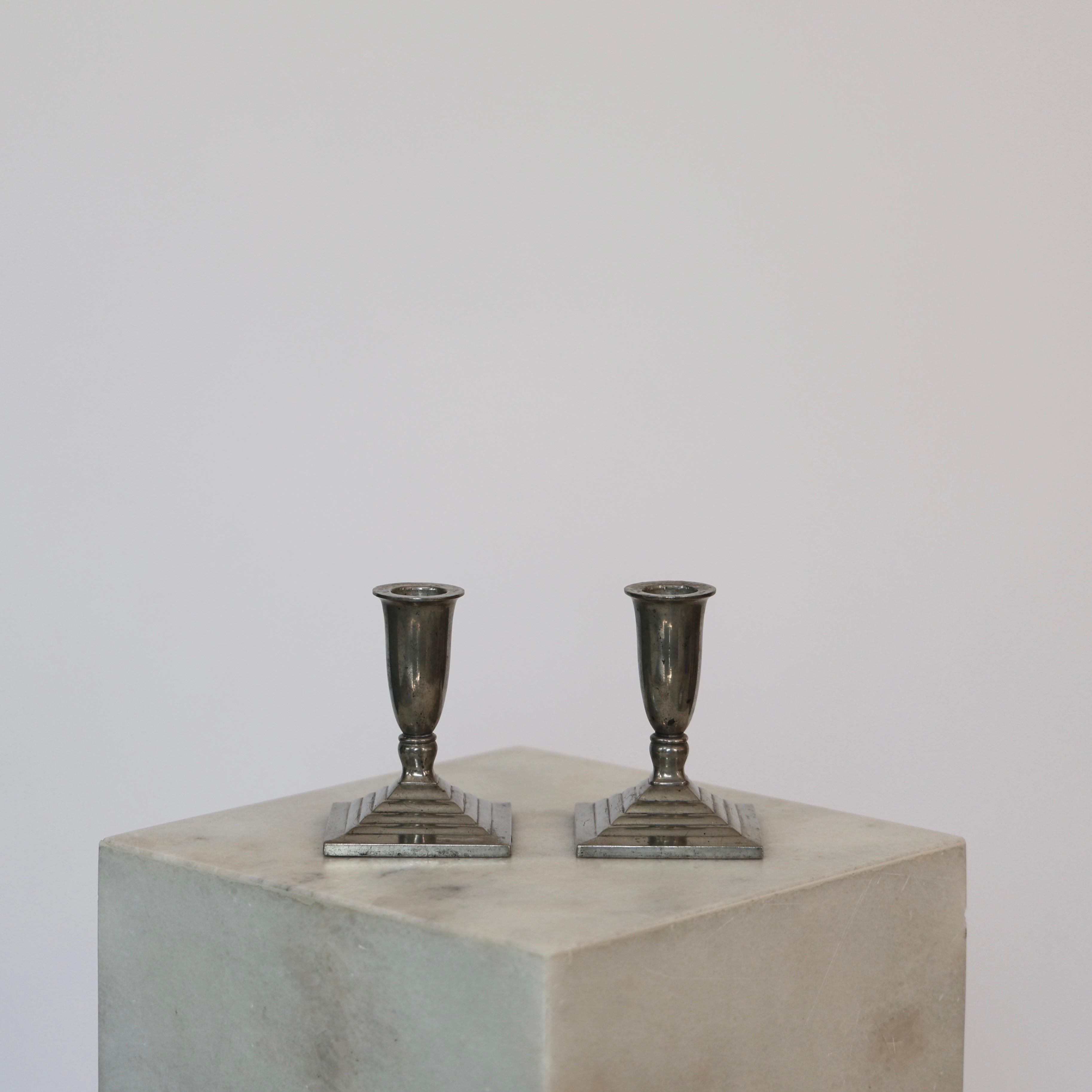 Set of Delicate Candlesticks designed by Just Andersen in 1930s. 

* Pair (2) of pewter candlestick holders on a cannellated square foot
* Designer: Just Andersen
* Manufacturer: Just Andersen
* Style: 1455
* Year: 1933
* Condition: Good vintage