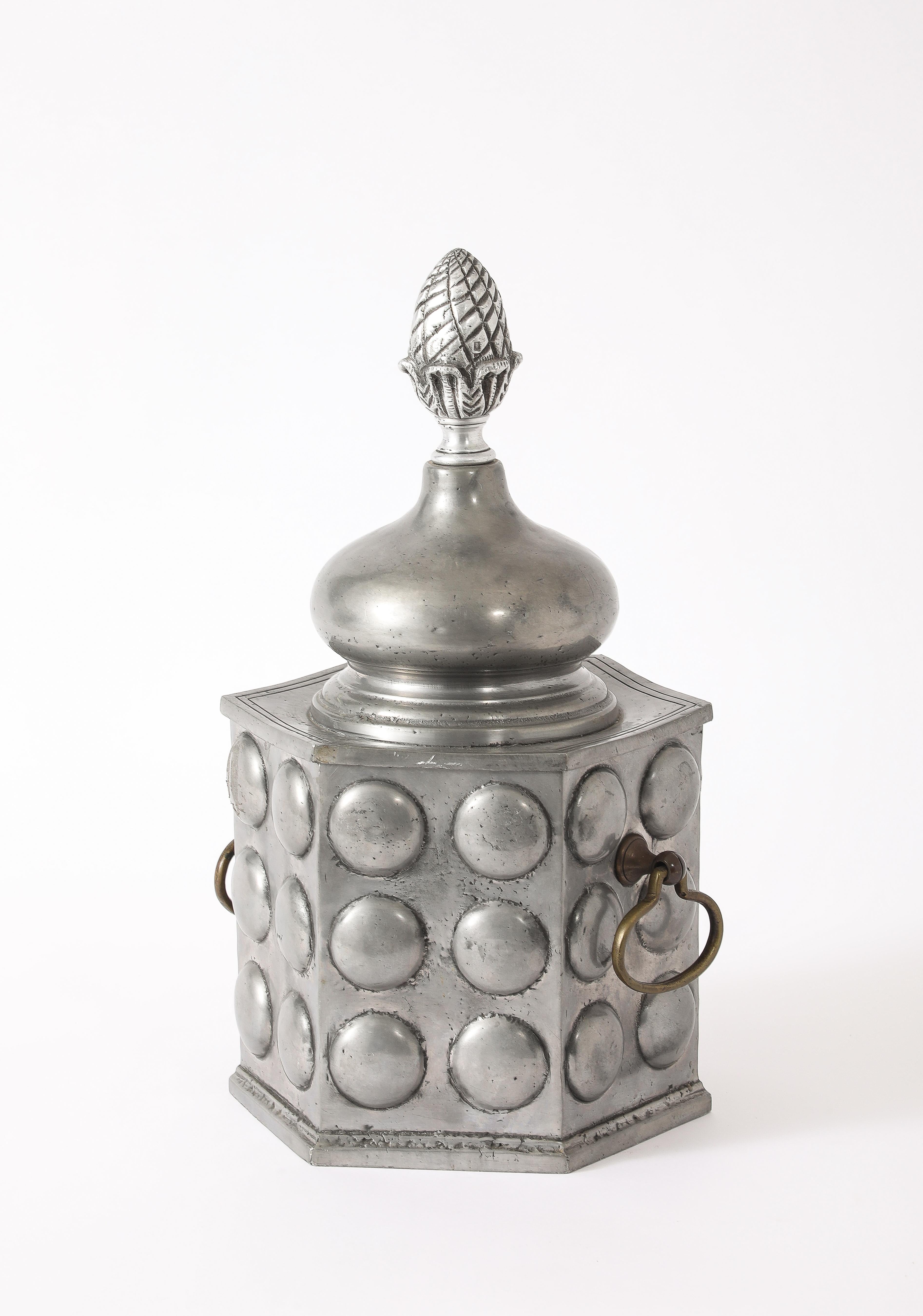 A finely crafted pewter ice bucket with silver plated handles and a pinecone finial.
