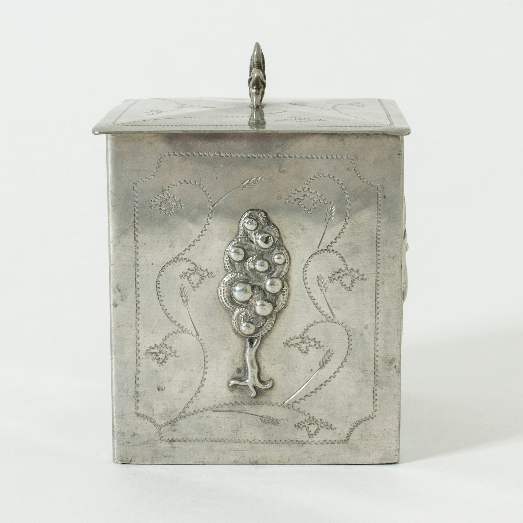 Beautiful pewter jar by Harald Linder, with a biblical motif. On the sides, reliefs depict Eve, Adam, a tree and a snake. Lovely etched decor and a leaf knob on the lid. Wooden inside.
    