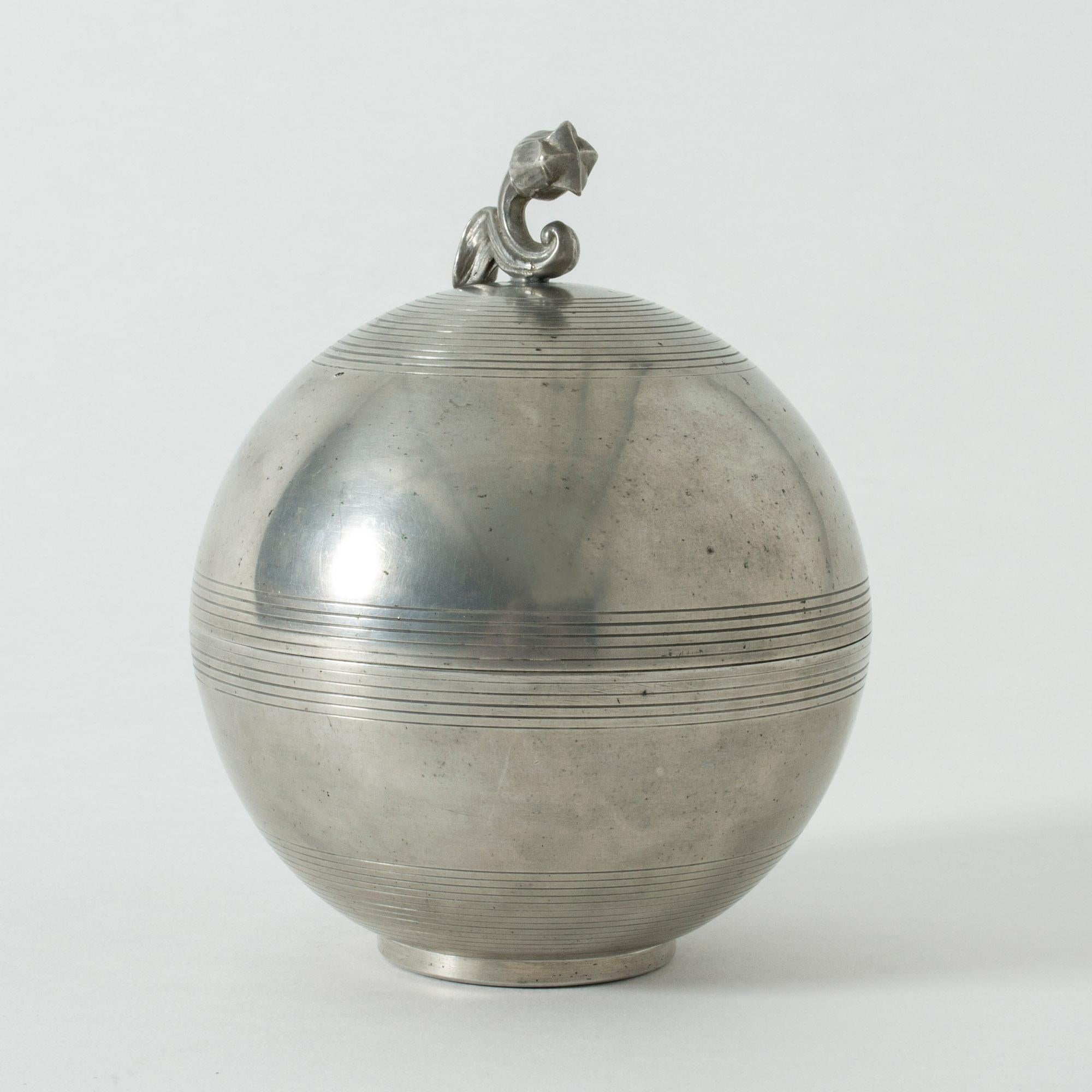 Beautiful pewter jar by Sylvia Stave, in a smooth, round design with decorative stripes. Adorned with a stylized tulip on the top.