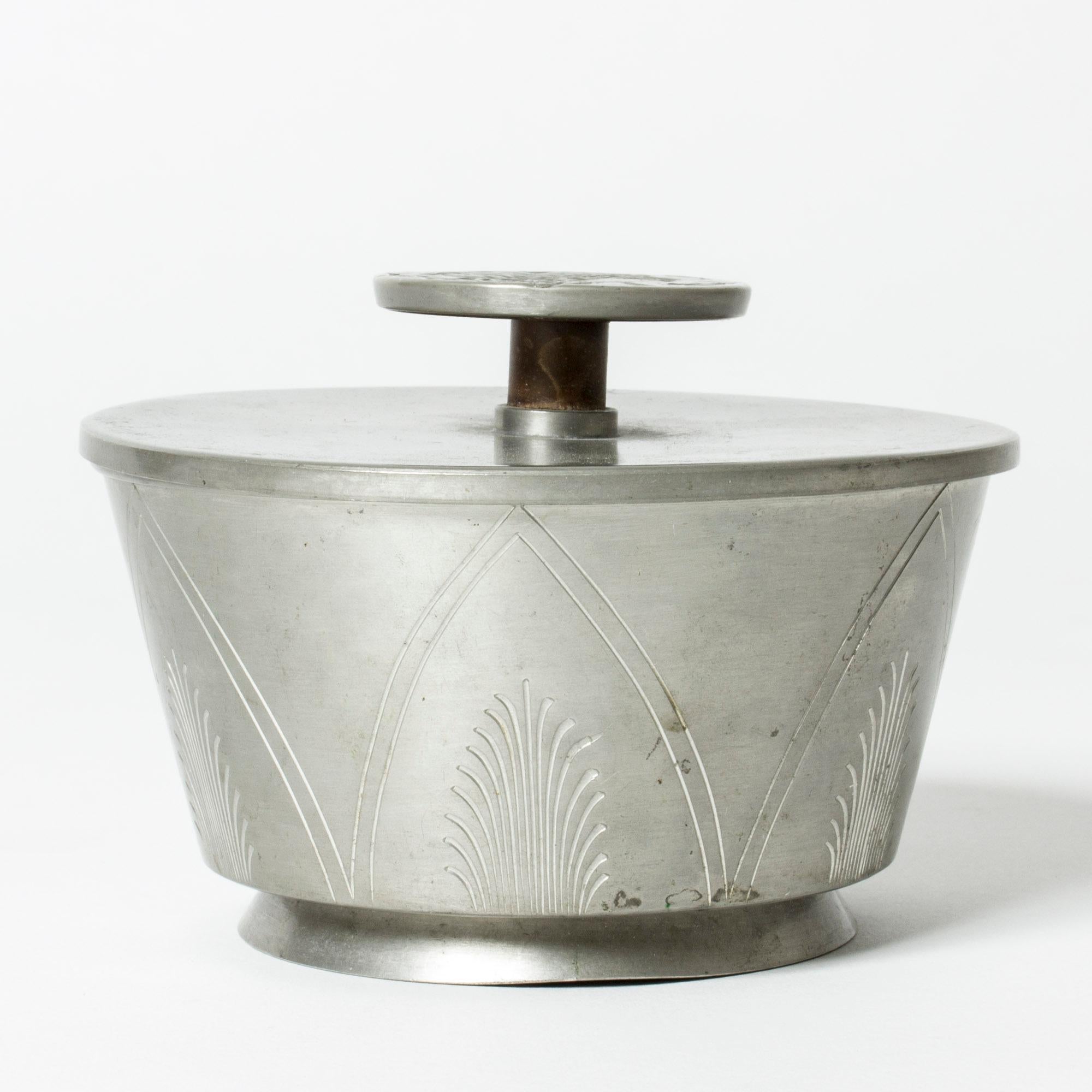 Pewter jar from Oscar Antonsson, in a beautiful design. Elevated knob on the lid, with a relief decor of a woman’s silhouette. Graphic, etched decor on the sides of the jar.