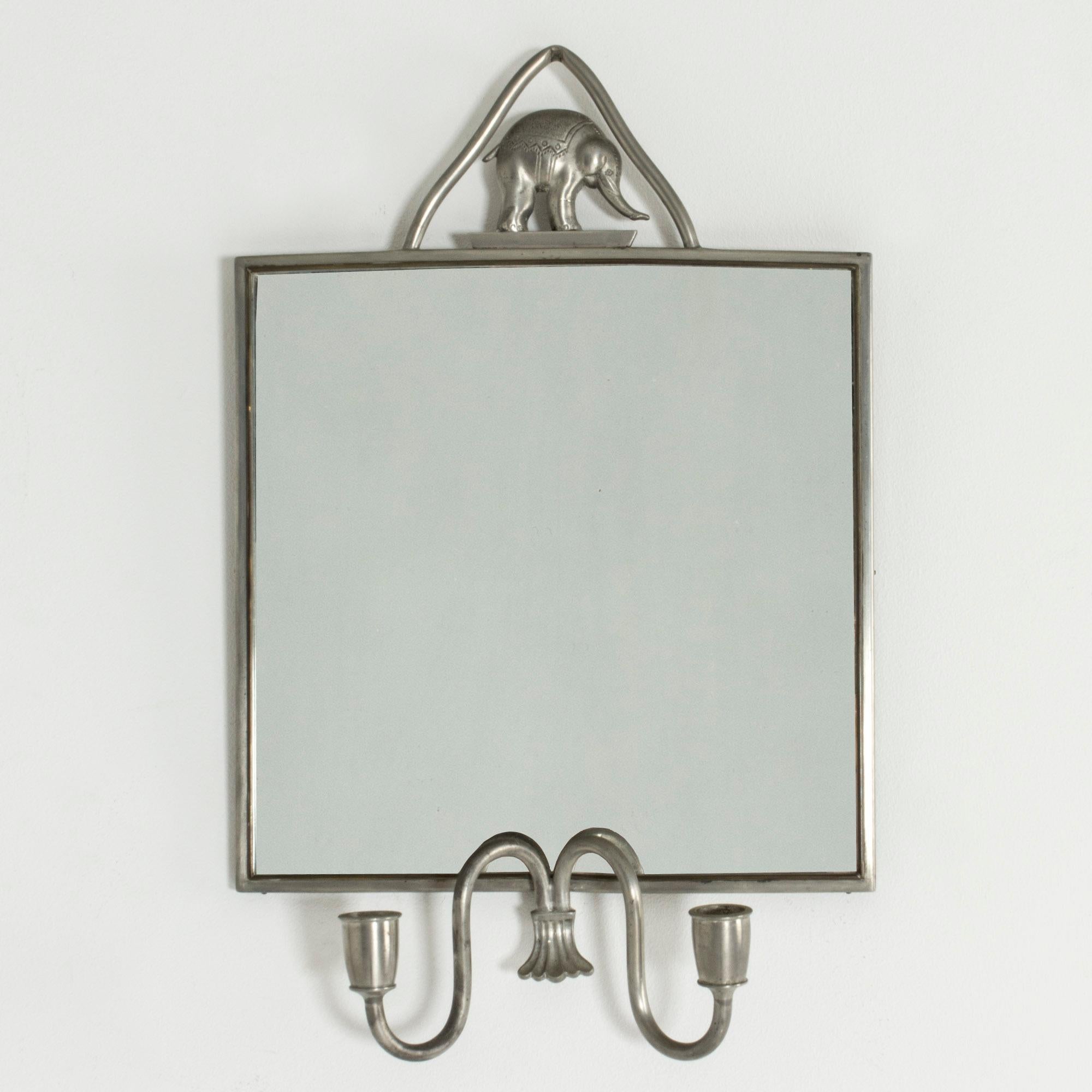 Adorable pewter wall mirror by Estrid Ericson, adorned with an elephant on top. Candleholders for two regular candles.