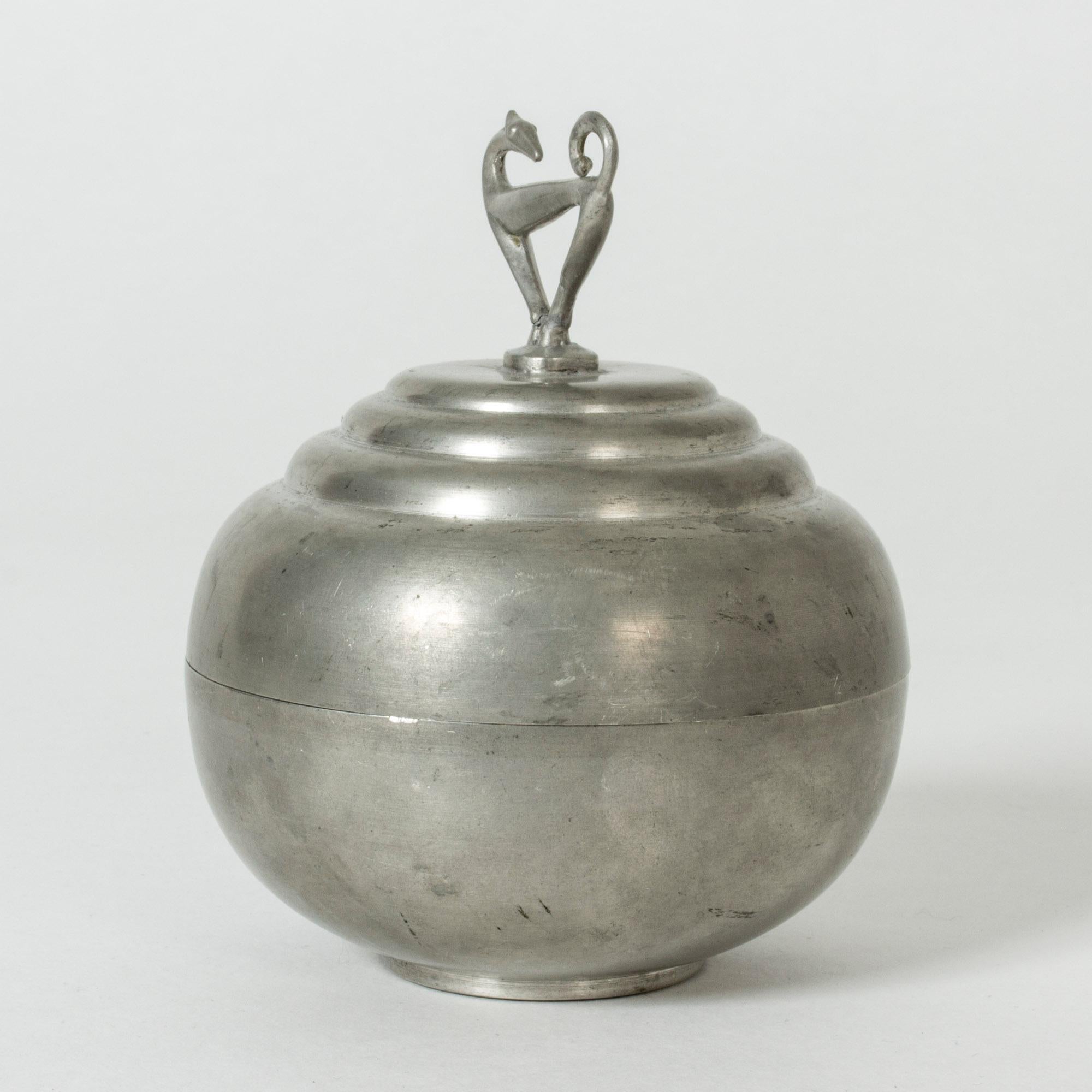 Cool pewter jar by Sylvia Stave, in a smooth, plump shape. A beautifully sculpted, graphic greyhound serves as decoration and knob.