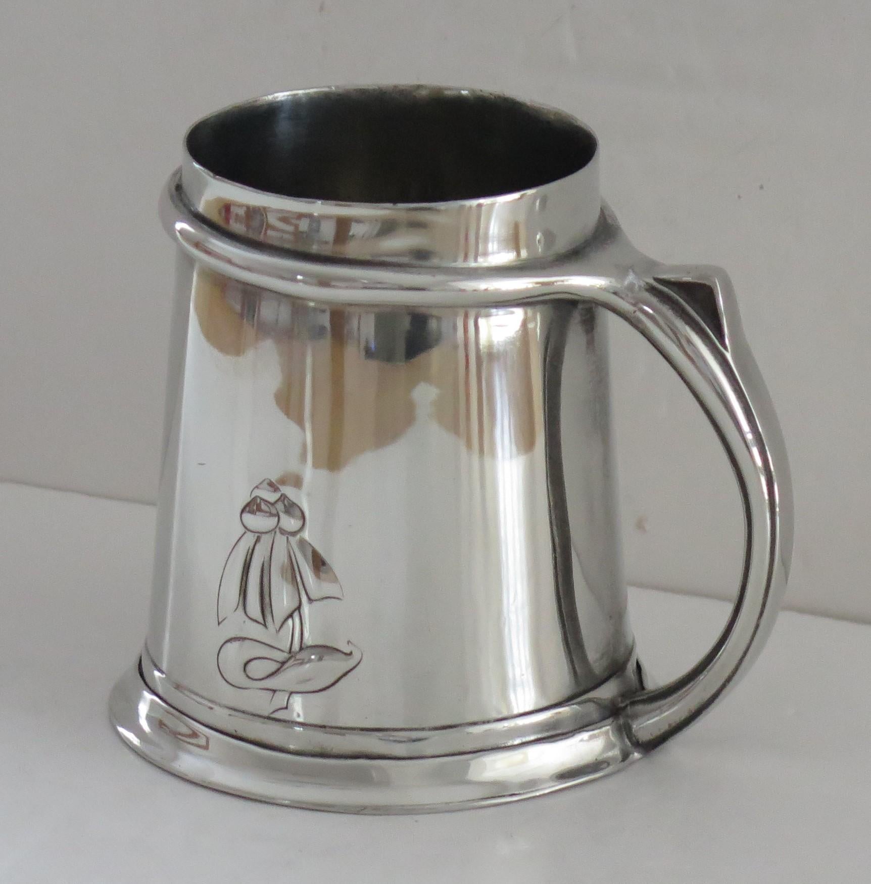 This is a good Pewter Tankard, designed by Archibald Knox, for Liberty & Co and marked Tudric with stamped Number 053, dating to the early 20th century, circa 1902.

The tankard is made of Pewter and has a polished and tapered hammered body with a
