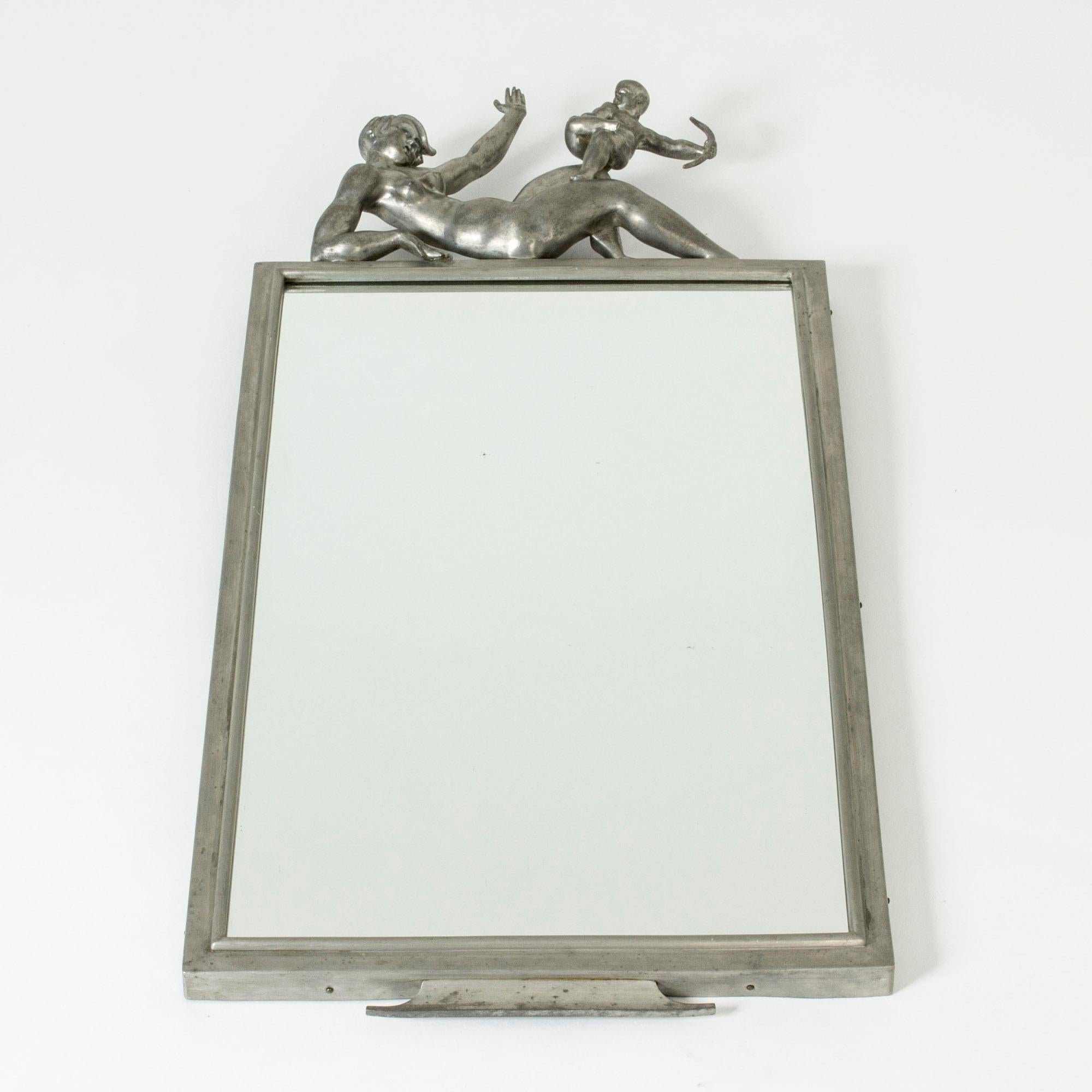 Stunning wall mirror by Thorwald Alef, made in pewter. The design is called “Amors spratt” (“Cupid’s Trick”). The top is adorned with a reclining woman with a naughty-looking Cupid on her knee, who she is trying to fend off. Beautifully sculpted.