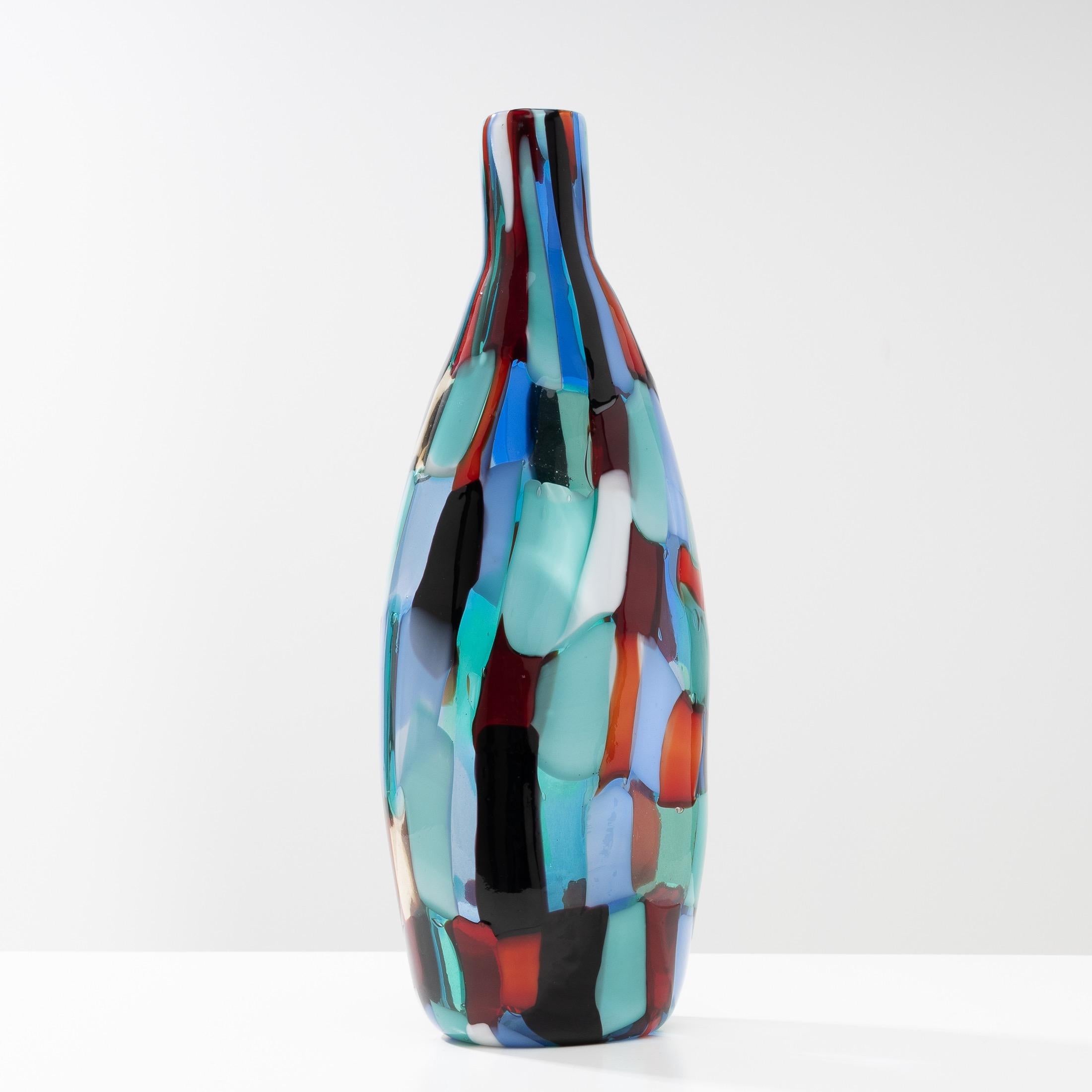 About the Pezzato arlecchino bottle shaped vase by Fulvio Bianconi
Mouth-blown vase, the model designed in 1950.
This color variant is often called “Arlecchino” by collectors. It is an arrangement of mosaics in shades of green, sapphire blue, milk