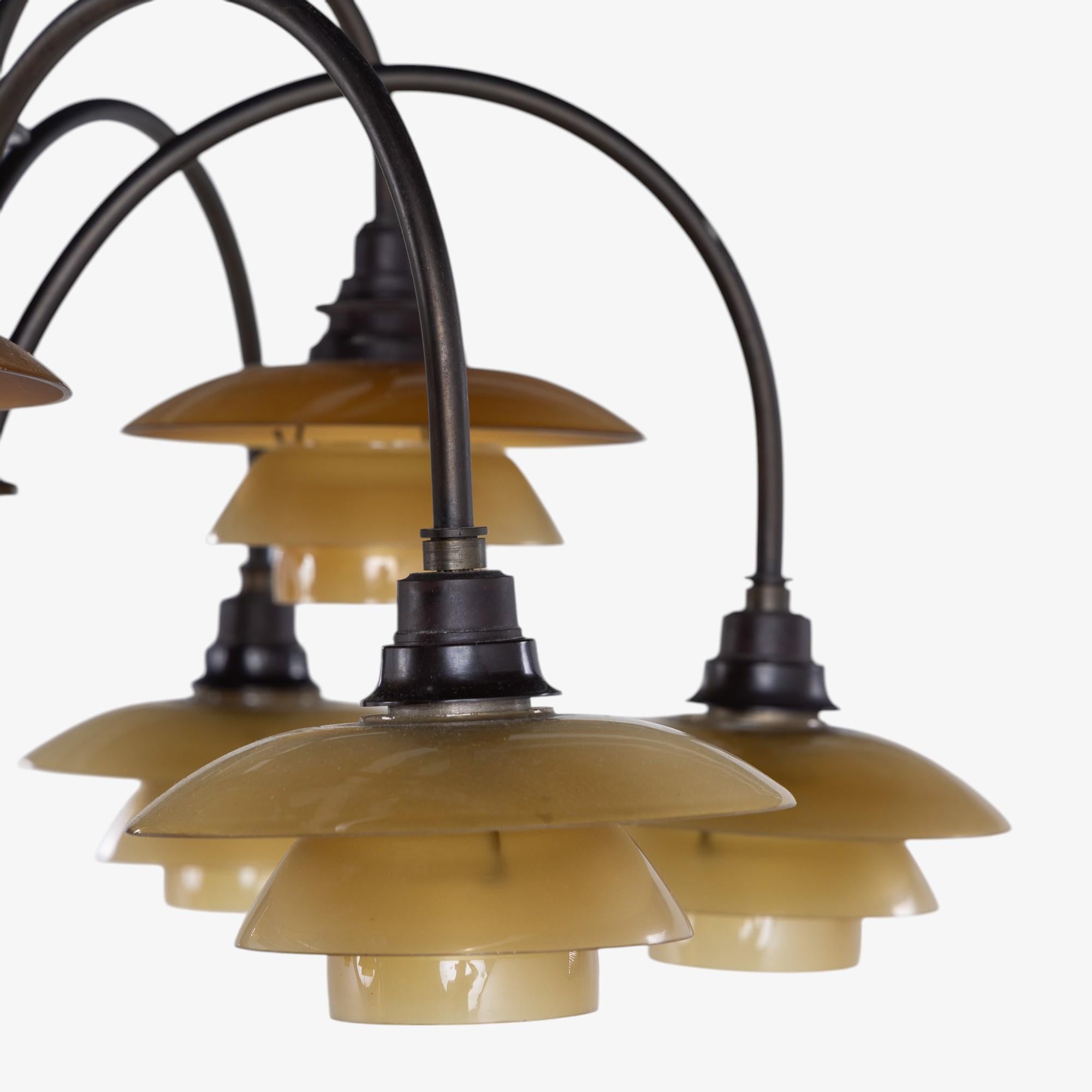 PH 1/1 - Lampadario 'Bombardementkrone', in ottone brunito con paralumi in vetro ambrato. Con il timbro 
