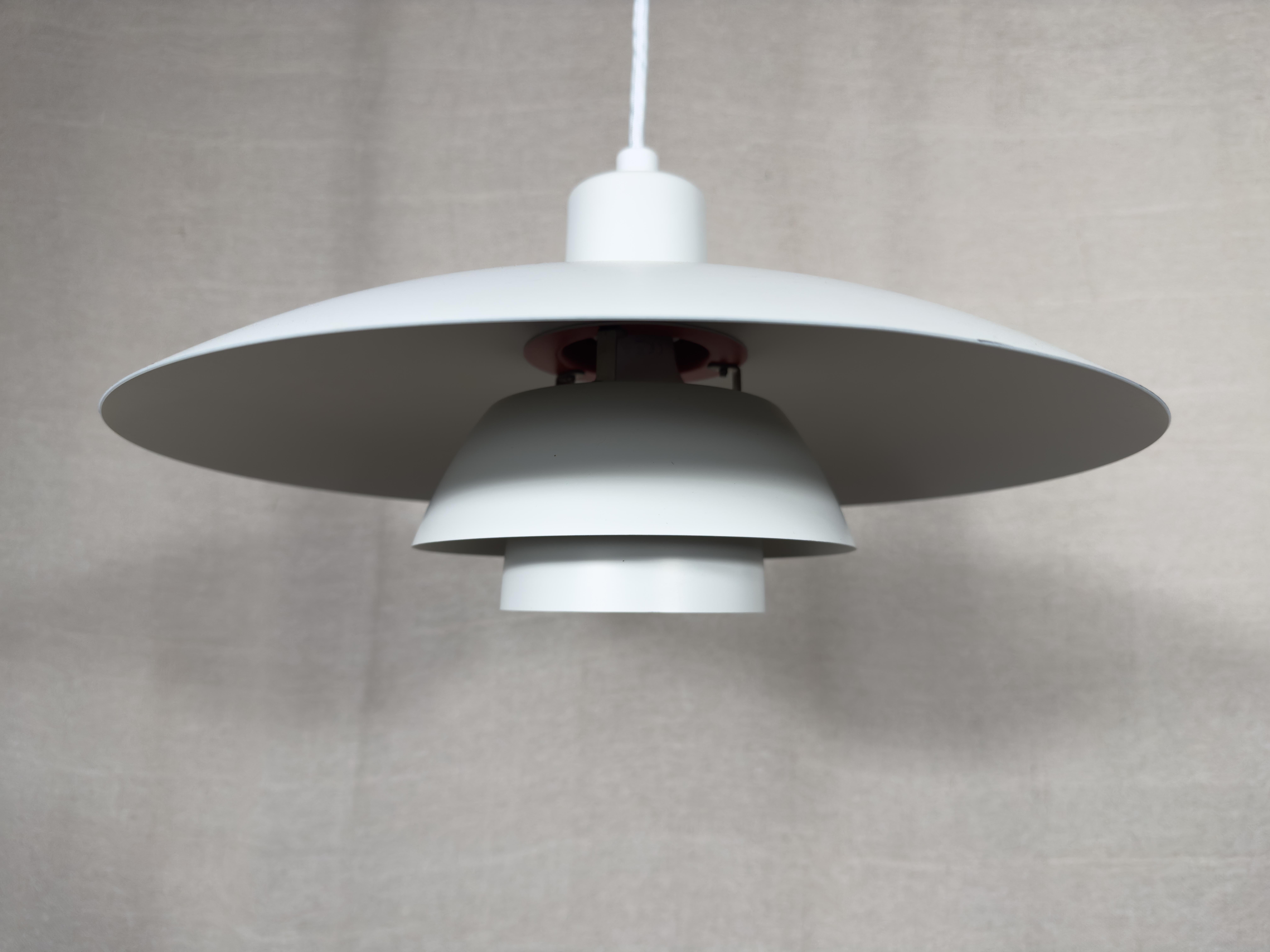 Realizzata e disegnata dall'iconico Poul Henningsen per la casa danese Louis Poulsen, questa PH3 è realizzata in alluminio e dipinta nella classica tonalità bianca. Il bianco brillante contrasta magnificamente con i riconoscibili accenti arancione