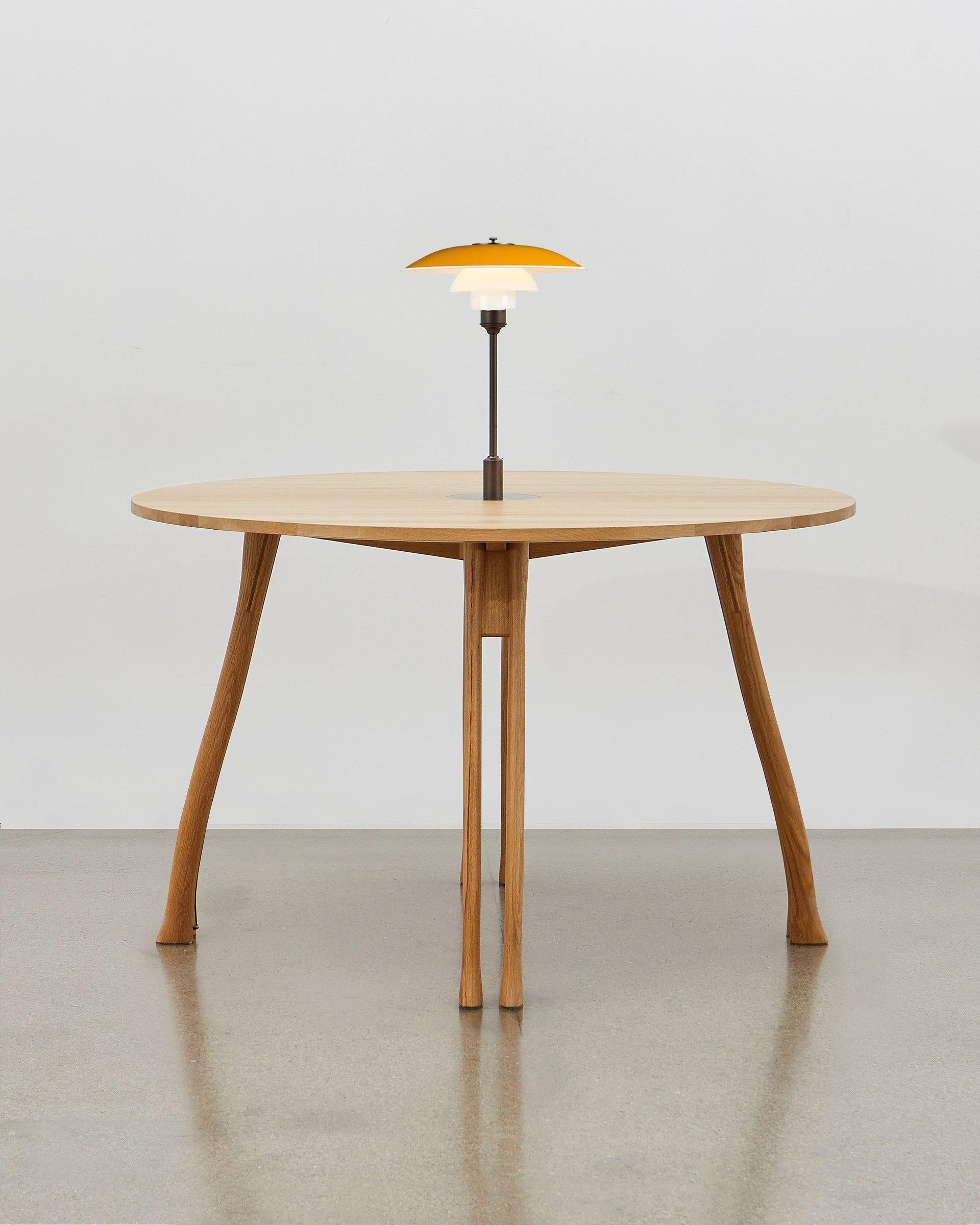 Inspiré par l'humble manche de la hache, Poul Henningsen a utilisé cette forme familière et tactile comme base pour les pieds de cette table polyvalente.

Ce meuble reste fidèle aux valeurs fondamentales qui ont motivé son concepteur : il s'agit