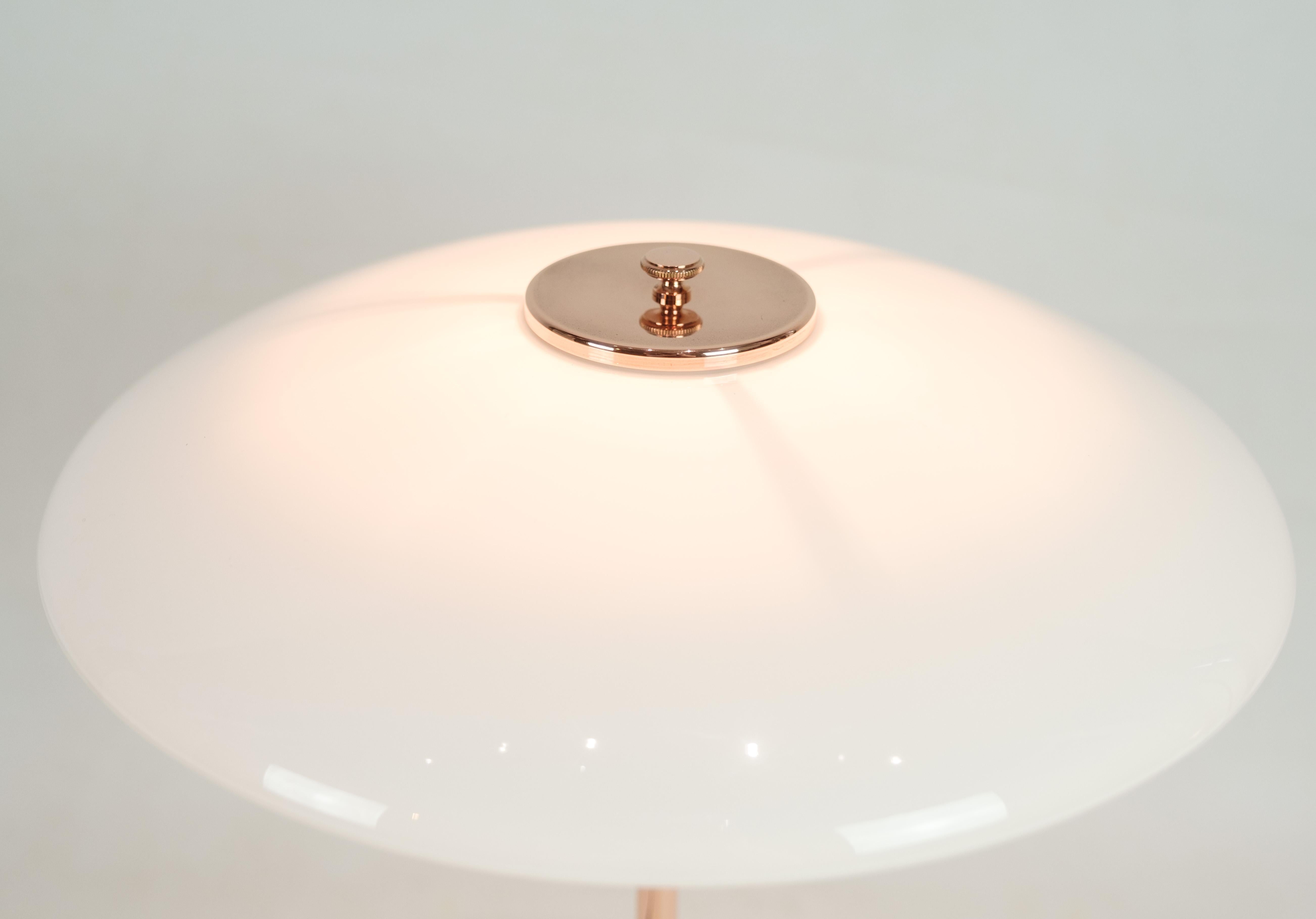 PH Table lamp, model PH3½-2½, is a limited edition designed by Poul Henningsen and manufactured by Louis Poulsen. This lamp, made of copper, has an upper shade in copper and two lower shades in white opal glass. An additional upper screen in white