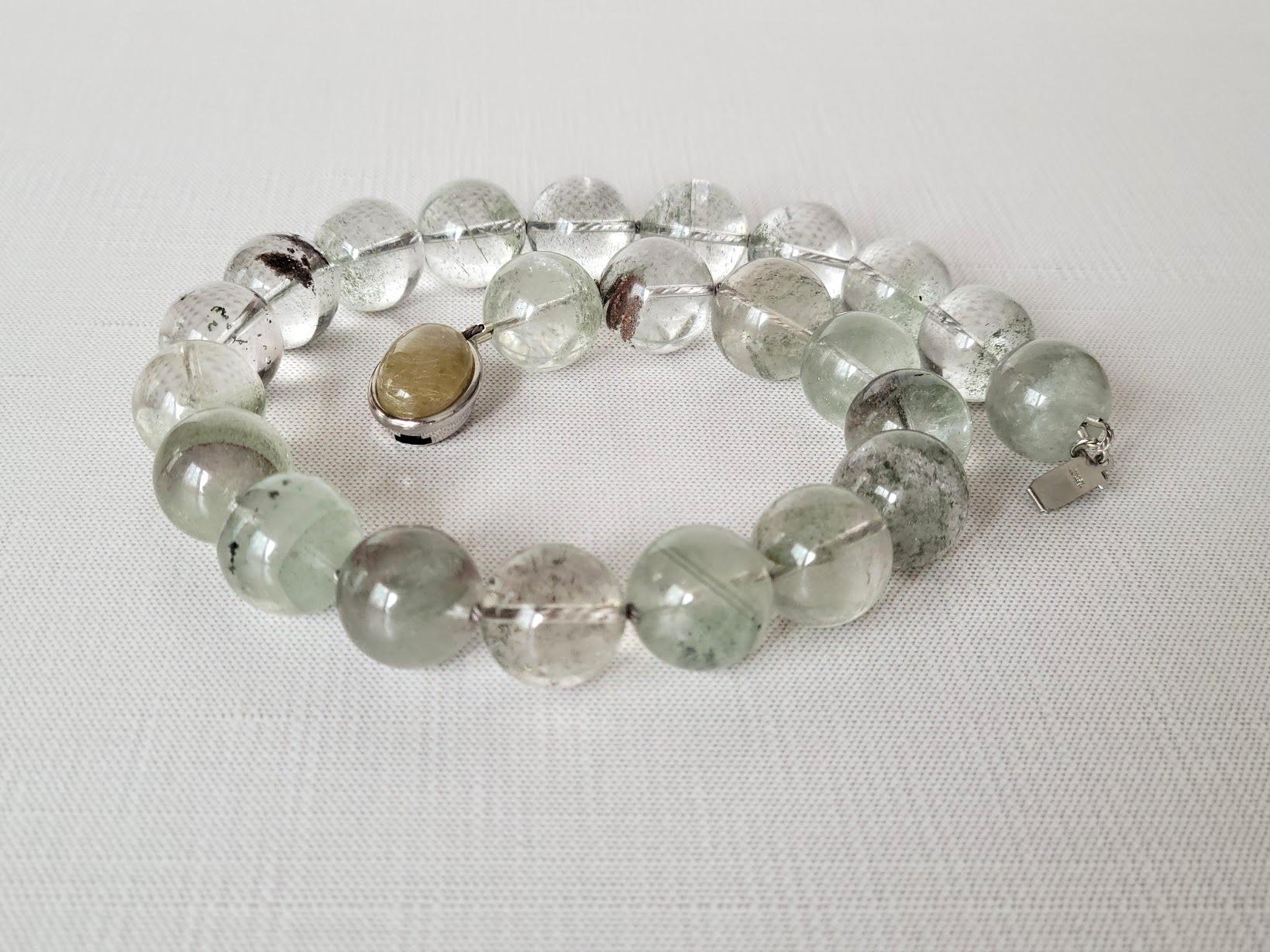 Siamo entusiasti di presentare l'ultima novità della nostra collezione: una splendida collana annodata di quarzo fantasma. Lunga 44,5 cm, questa collana è composta da perline rotonde lisce (17,5-18 mm) di colore grigio-verde. Il quarzo fantasma è