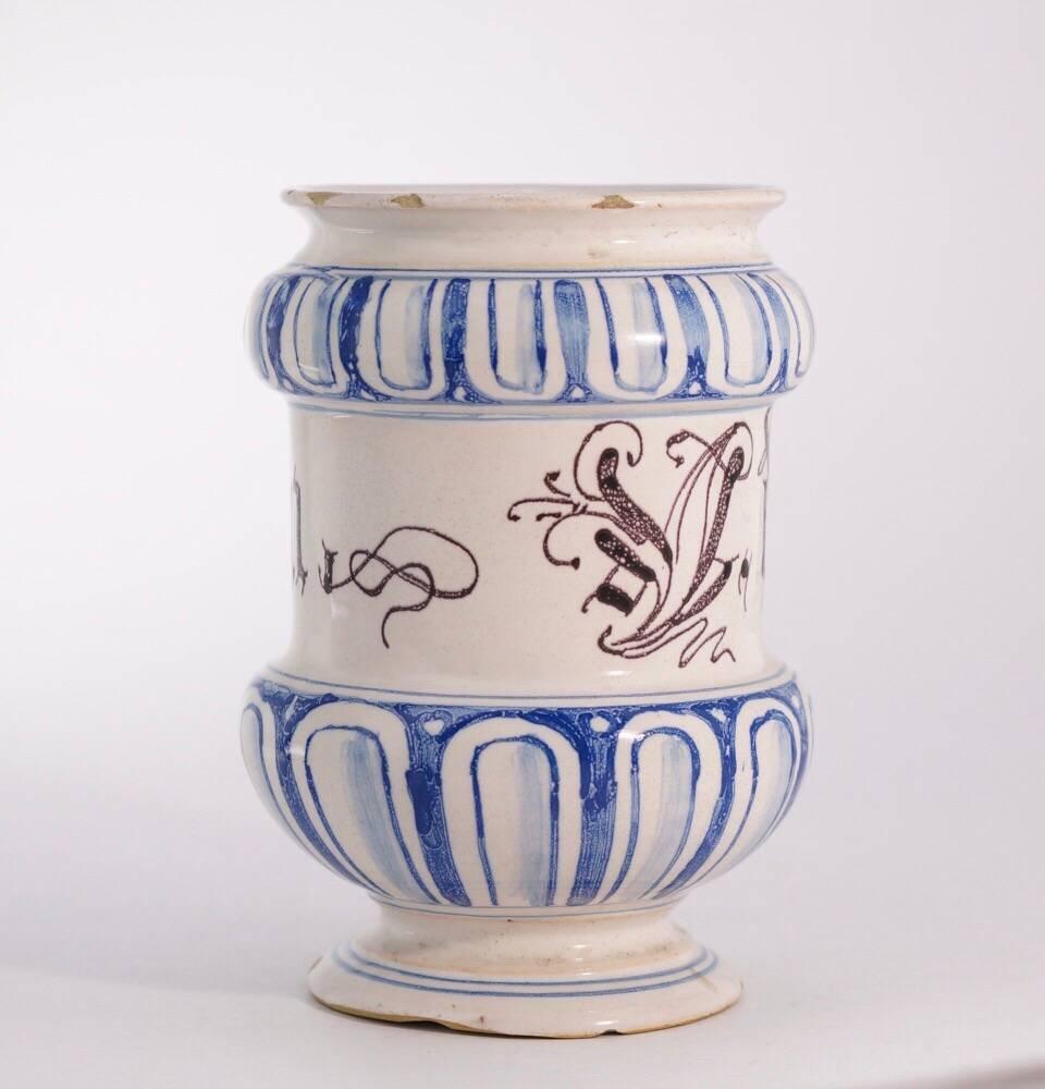 Italian faience Albarello, of cylindrical footed form, decorated in blue with wide borders of simulated gadrooning to the swelling neck and base, inscribed around the body in gothic manganese script 'V. urapilatium'. Attributed to Savona, circa
