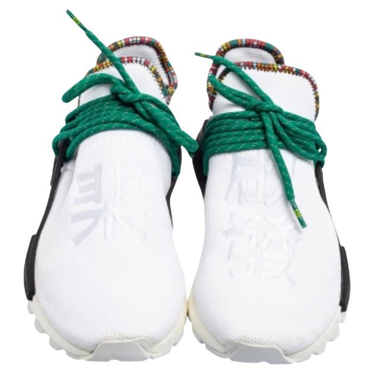 Bei den Pharrell x adidas NMD Sneakers dreht sich alles um Komfort und Style. Sie haben ein weißes Obermaterial, einen Schnürkäfig und eine gepolsterte Boost-Zwischensohle. Fersenlaschen, gestreifte Schnürsenkel und ein mehrfarbiger Print am Kragen