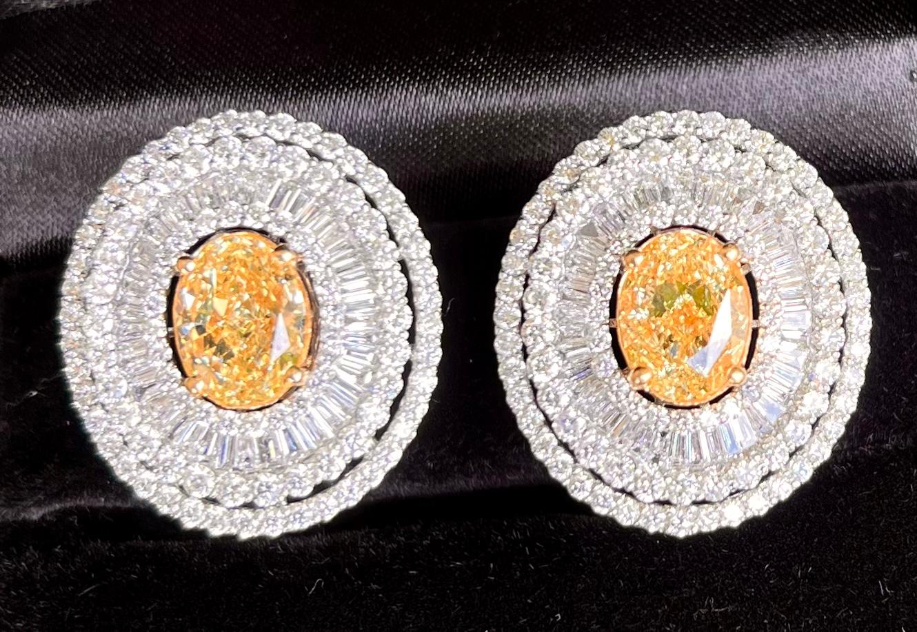 Phenomenal pair of ladies 18 karat white gold oval shaped diamond ballerina style earrings feature in the center of each earring one large oval modified brilliant cut natural fancy yellow diamond.  Each fancy yellow diamond is prong set in 18 karat