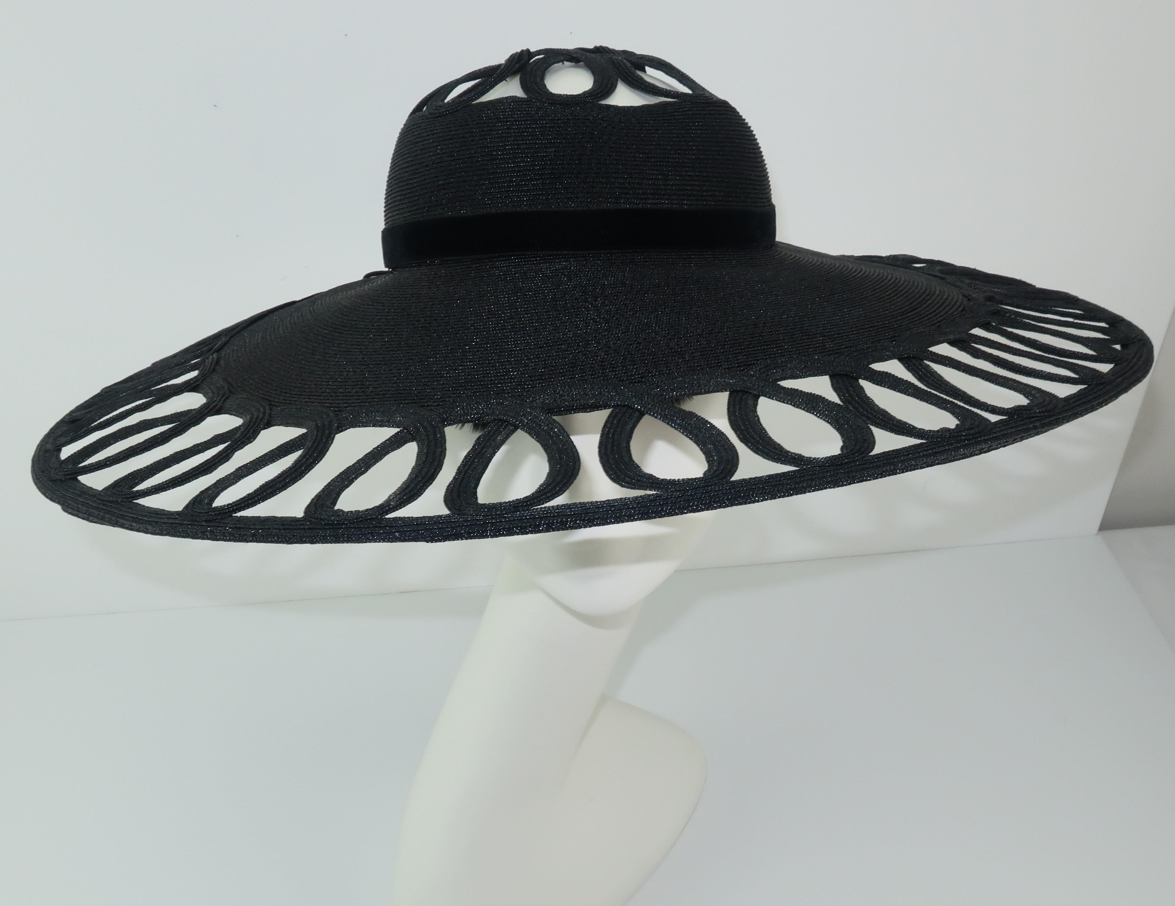 An uber chic C.1950 Phil Strann black straw hat with a velvet bow accent and a unique looped pattern at the crown and wide brim. The wide brim offers a dramatic silhouette perfect for special events or high style resort wear.  Very good vintage