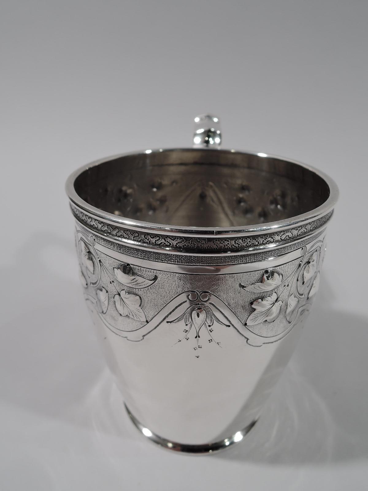 American classical coin silver baby cup. Made by Krider & Biddle in Philadelphia. Gently curved and tapering body and capped scroll-bracket handle. Stylized flowers and crowned female heads with flowing tresses in strapwork frames. A great gift for