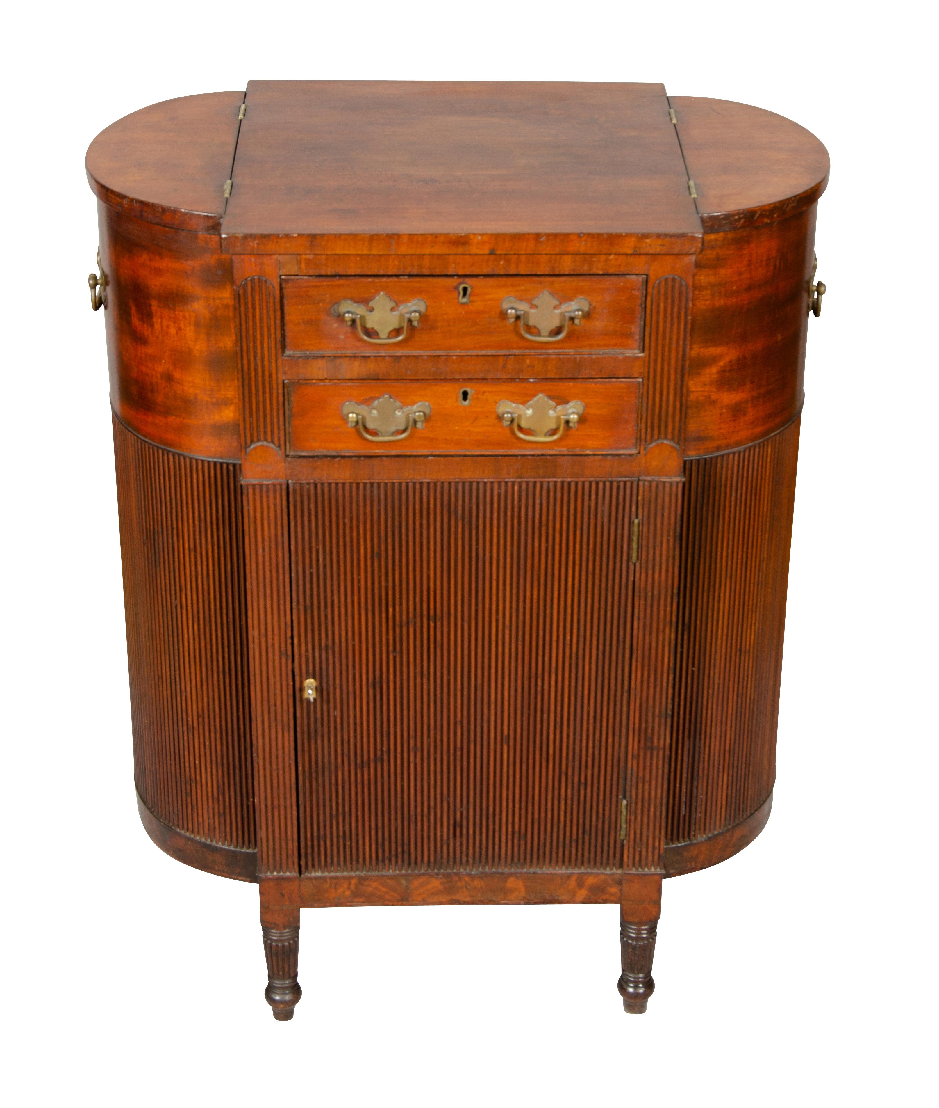 Rectangular top with rounded hinged ends opening to compartments over two drawers that open from both sides over a hinged door with tambour front and ends and back raised on turned tapered legs. Descended in an old Boston family.