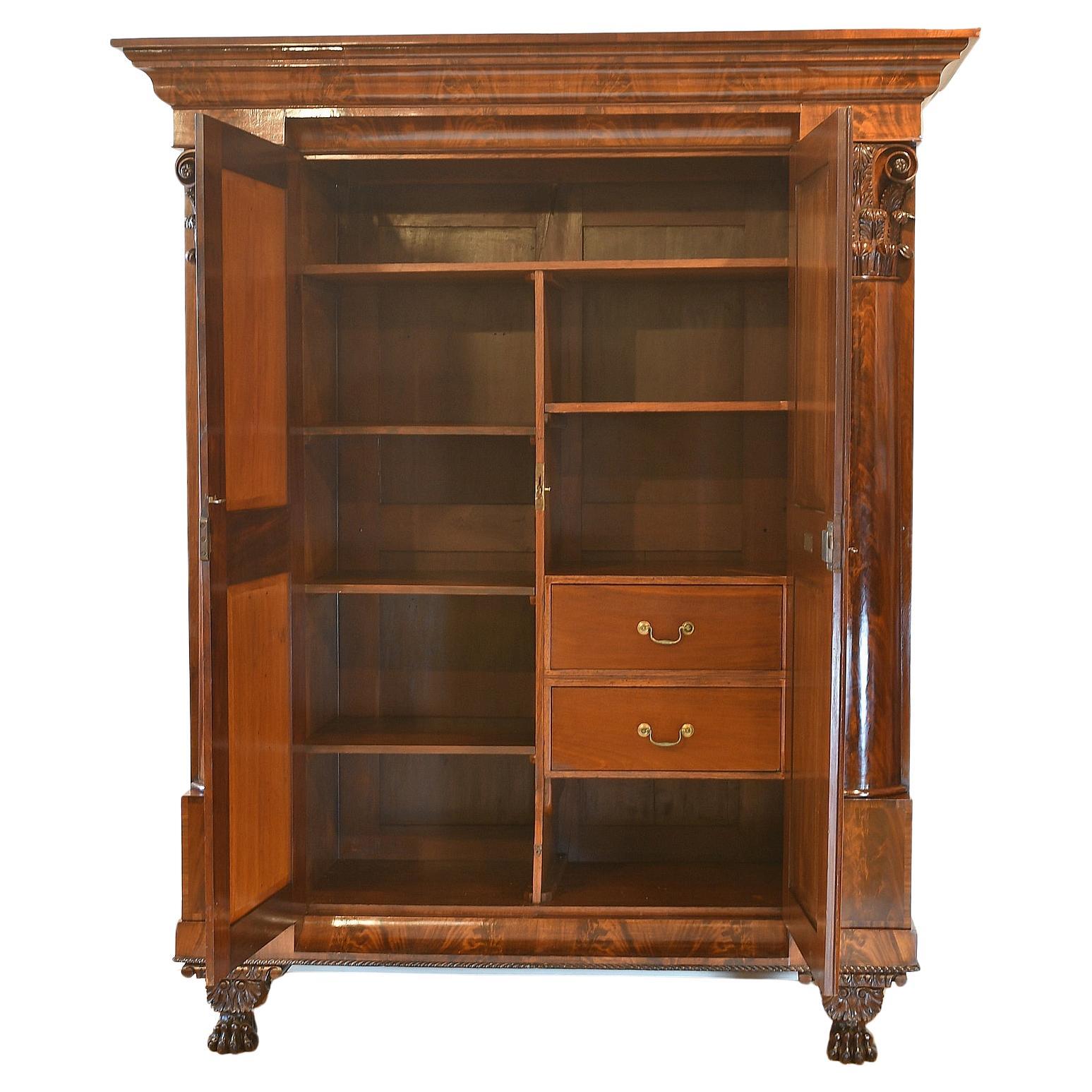 An exceptional American Federal wardrobe from Philadelphia in fine West Indies mahogany. Features split cylindrical columns with elaborate acanthus-carved Corinthian capitals flanking doors with book matched, crotch-mahogany panels. The stepped