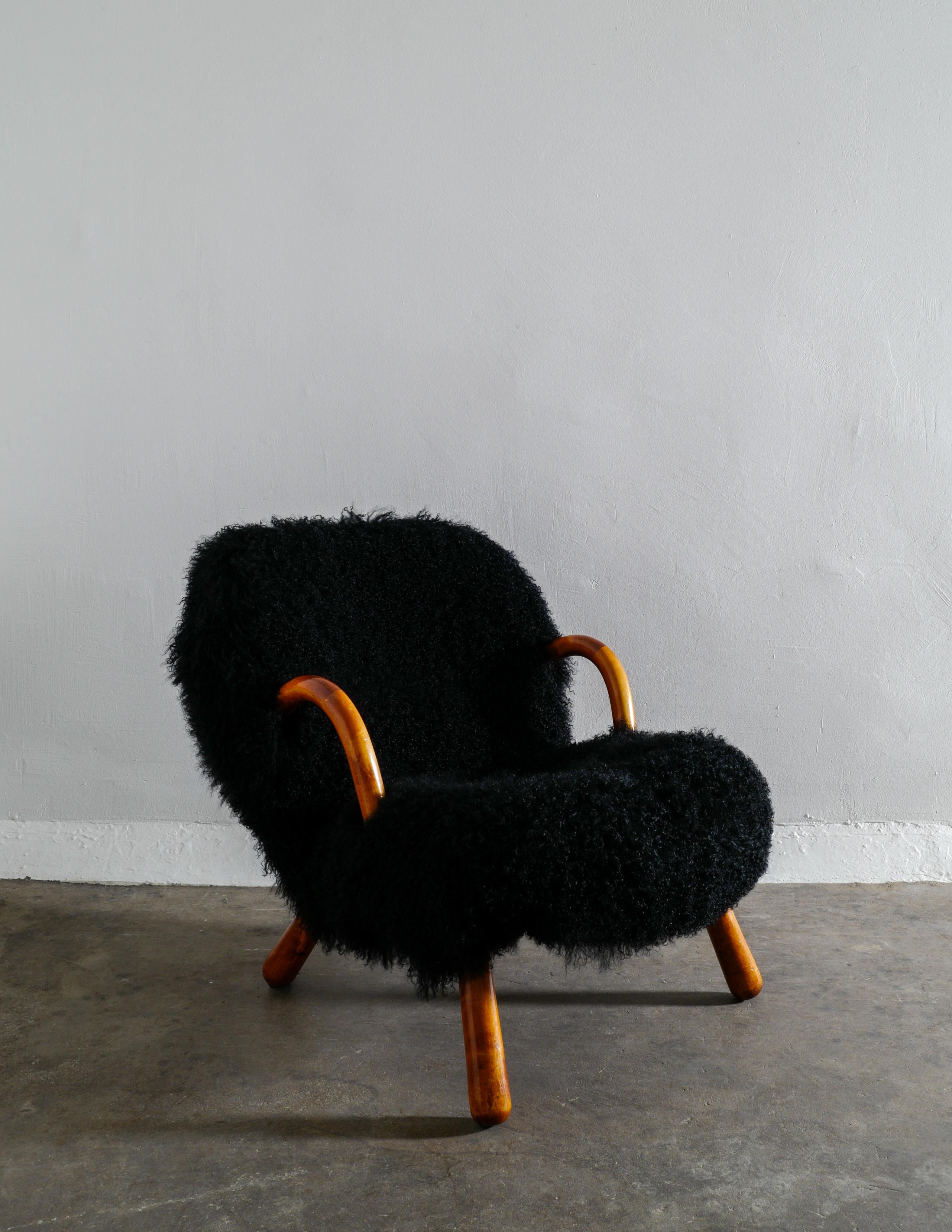 Rare clam chair designed by Philip Arctander and produced by Vik & Blindheim, Norway in the 1940s. Newly restored and upholstered in a black curly sheepskin. In good vintage condition with small signs from age and use. Original patina in arms and