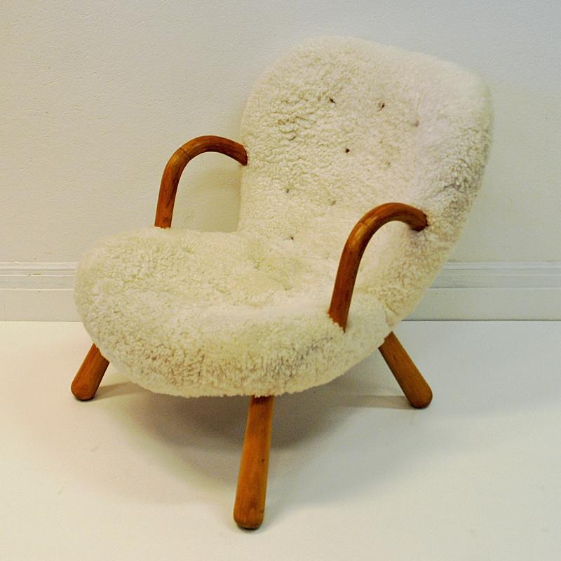 The beautiful Clam chair (also named Muslingen) was designed by Danish designer Phillip Arctander in Denmark 1944. Reupholstered a couple of years ago in white sheepskin. Original oak arms and legs. This Clam easy chair has matching buttons in light