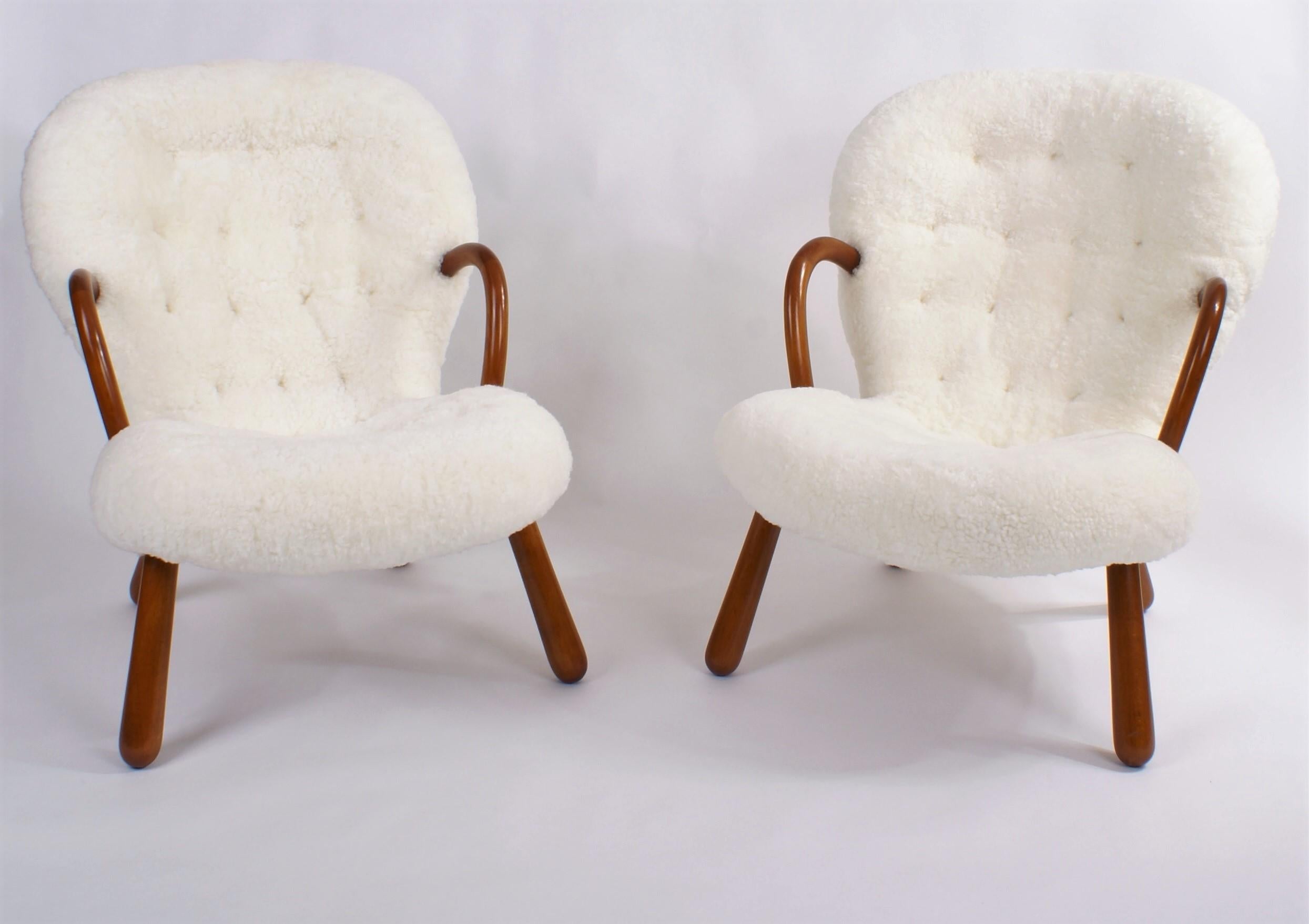 Pair of Philip Arctander 'clam' easy chairs in white sheepskin and legs in stained beech. Buttons in leather. Designed 1944. This pair is from the 1950s.

Price is for the pair.

 