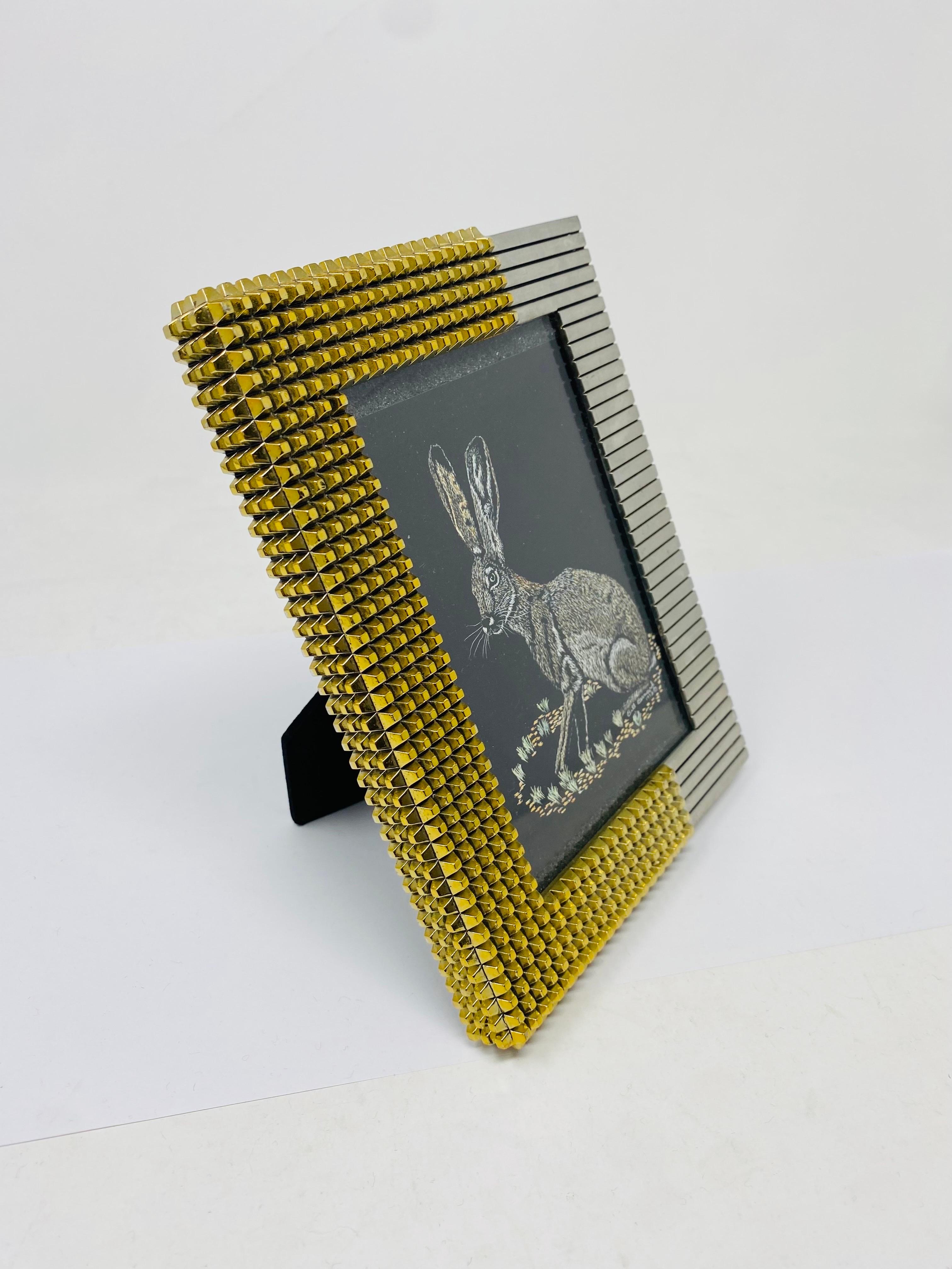 Marco de fotos elegante y arquitectónico chapado en plata y oro.  Un legado en diseño, Philip Crangi diseñó esta pieza con estilo y detalles arquitectónicos.  Esta hermosa pieza rezuma brillo metálico plateado y dorado al estar completamente