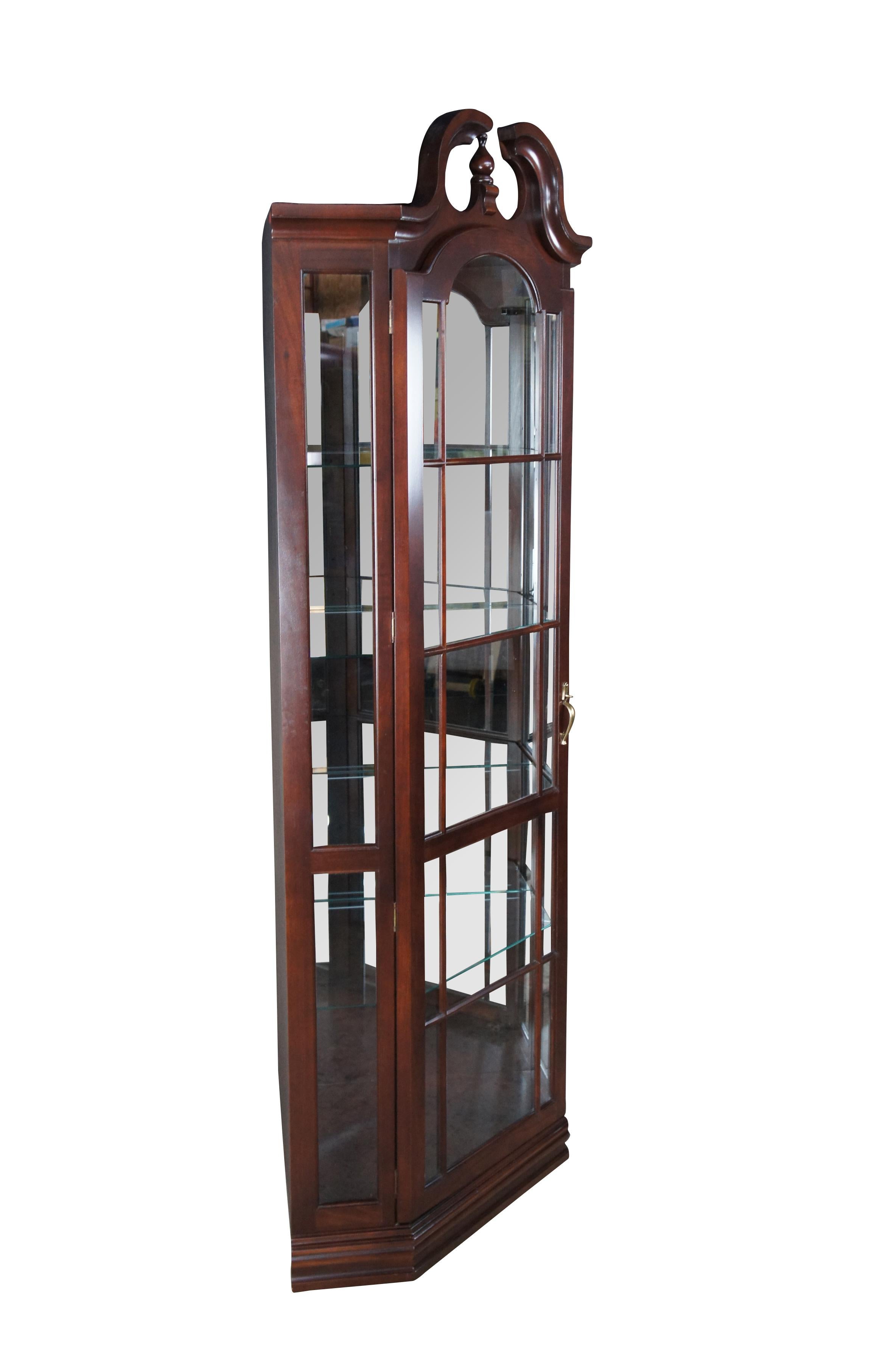 Philip Reinisch Queen Anne style corner display cabinet, circa 1990s.  Made from cherry with an open pediment and lattice front.  Opens to four adjustable glass shelves with plate grooves.

Founded in 1932 in Chicago Illinois, Philip Reinisch
