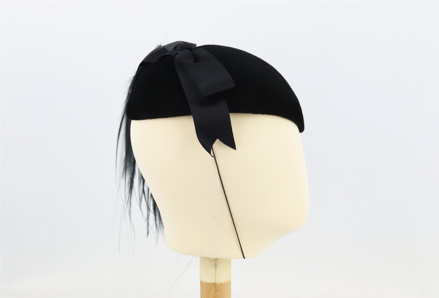 This fascinator by Philip Sommerville for Harrods is set on a teardrop-shaped base, this fascinator is made from wool-felt with feather and silk bow detail at the top. Black wool-felt. Elasticated strap fastening. 100% Wool. Does not come with box.