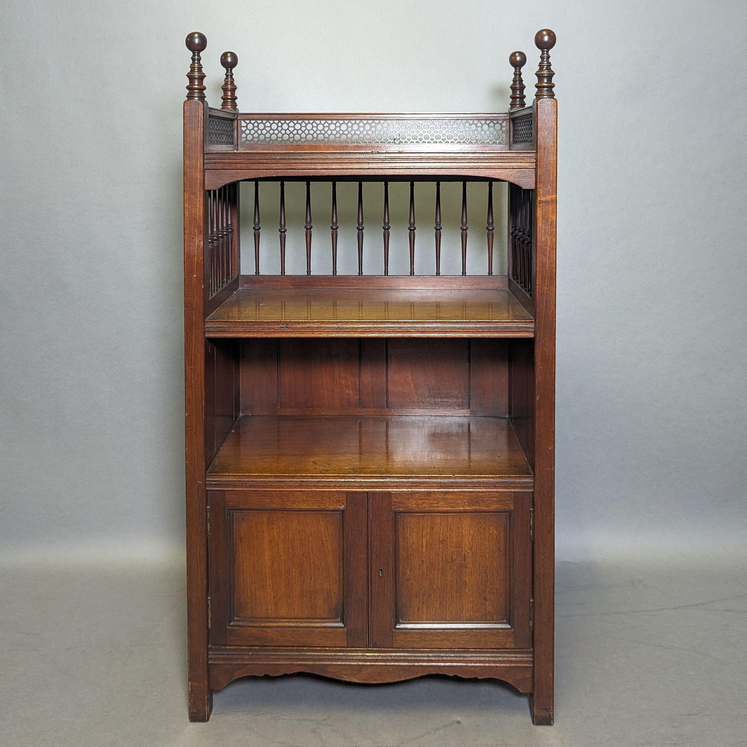 Philip Webb para Morris & Co. Un raro atril de nogal para partituras o folios con remates torneados alargados, decoración circular calada y una galería inferior torneada en tres cuartos con tres estantes abiertos y un armario en la base.Una versión