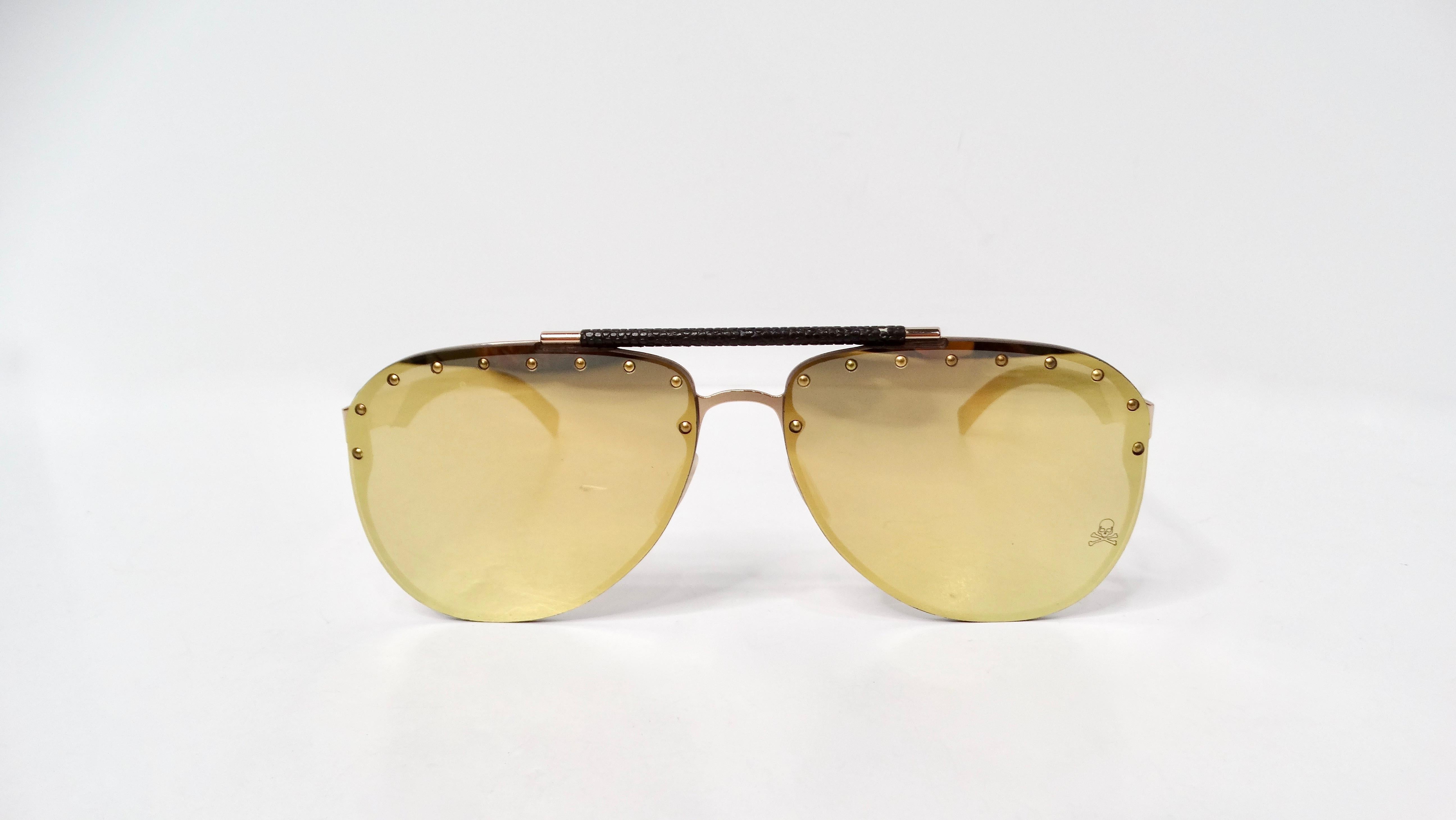 Elevate your eyewear collection with the Philipp Plein Calypso Studded Mirrored Aviator Sunglasses. These stunning sunglasses feature a chic design characterized by studs adorning the front of the lenses, creating a bold statement that captures