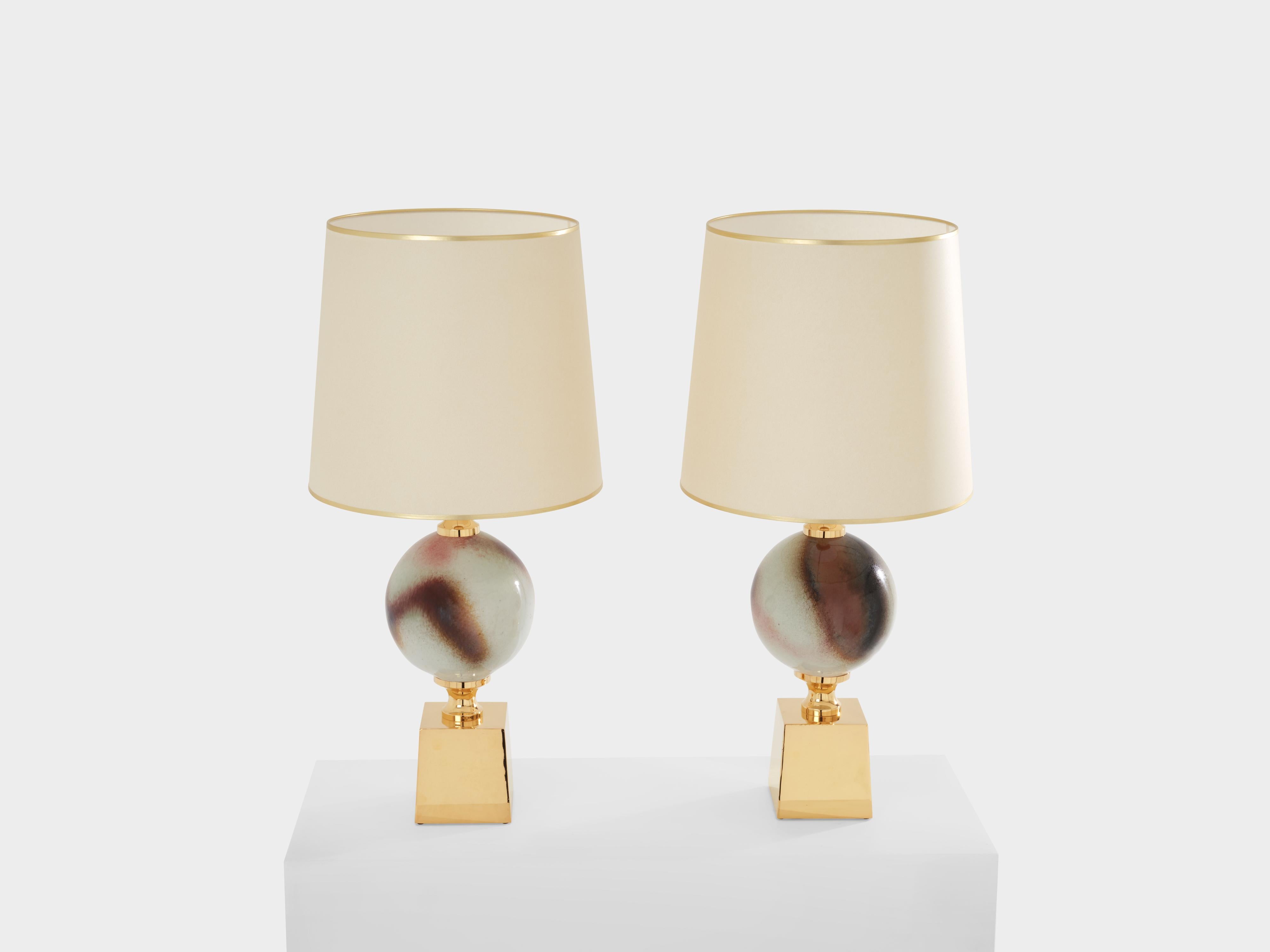 This large pair of lamps was designed by French designer Philippe Barbier in the 1970s. The two spheres are made of glazed ceramic in rich shades of brown and cream, with brass fixtures and a large brass base. These lamps are typical of Barbier’s
