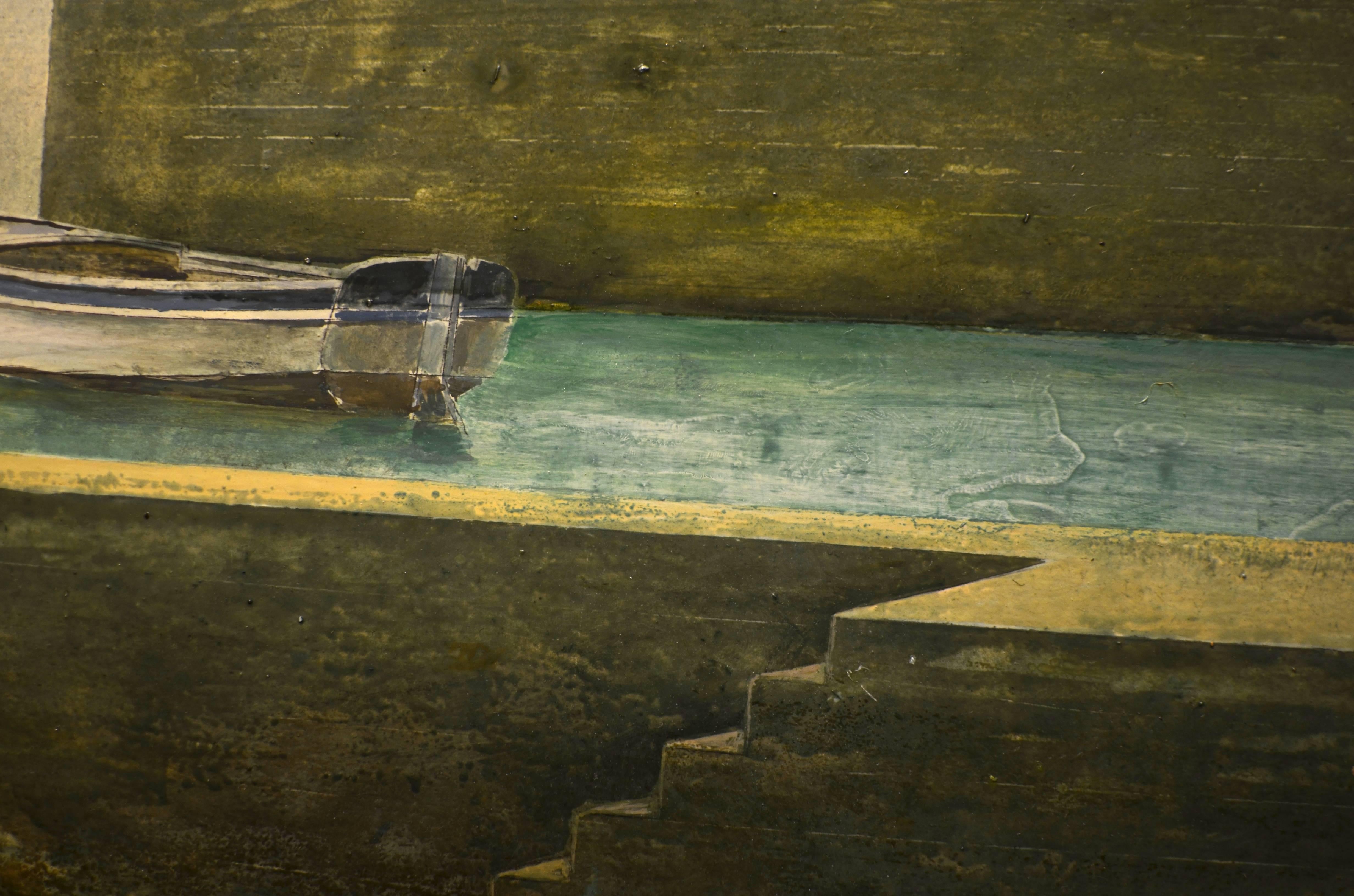 This oil painting on board depicts a lonely house with a pool and boat looking out into an ocean without water. Though a surrealist painting, the artist paints with extreme precision and detail. The color palette combines dark shadows with light,