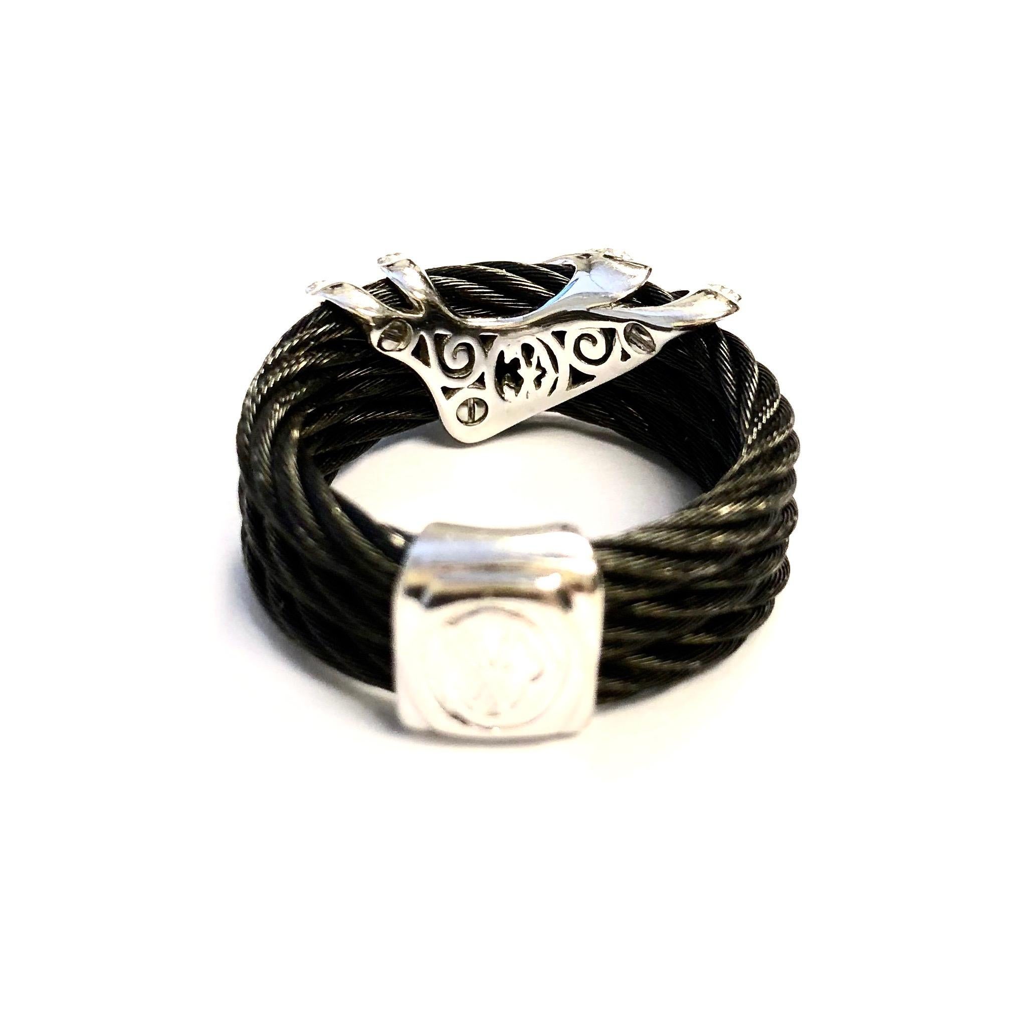 Crafted in 18K white gold and black stainless steel cables, the ring features a diamond set double chevron on the front. 
Nineteen round brilliant cut diamonds, approximate total weight: 0.20ct. Color: F-G, Clarity: VS
Measurements:
Width: 9 mm (