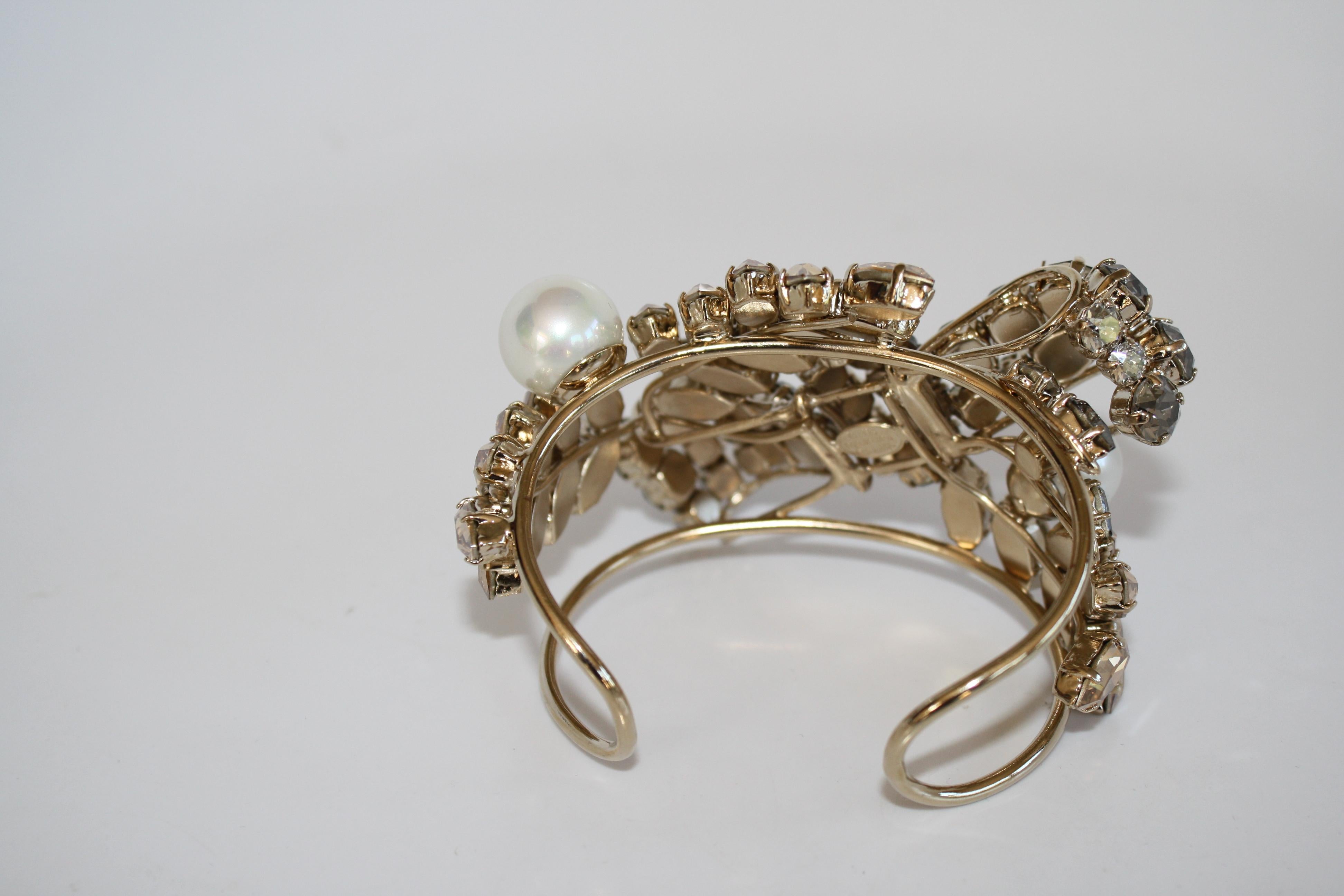 Swarovski Crystal bow and leaf motif cuff bracelet with glass pearls from Philippe Ferrandis. Cuff is malleable and can adjust to wrists both large and small.  