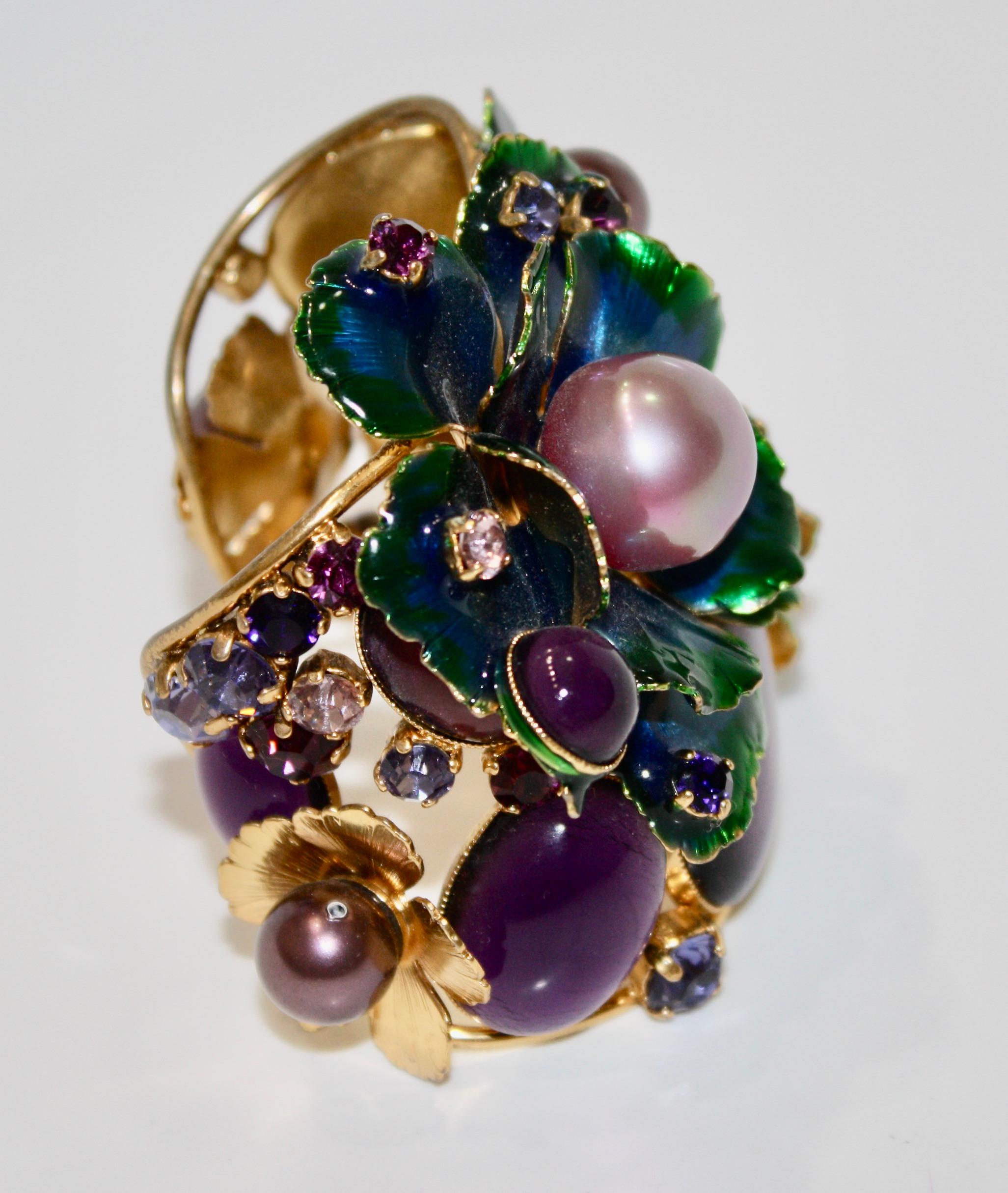 Enameled flowers in shades of blue and green, handmade glass pearls and Swarovski crystal. Cuff is adjustable with a gentle squeeze.
24-carat gilded brass.