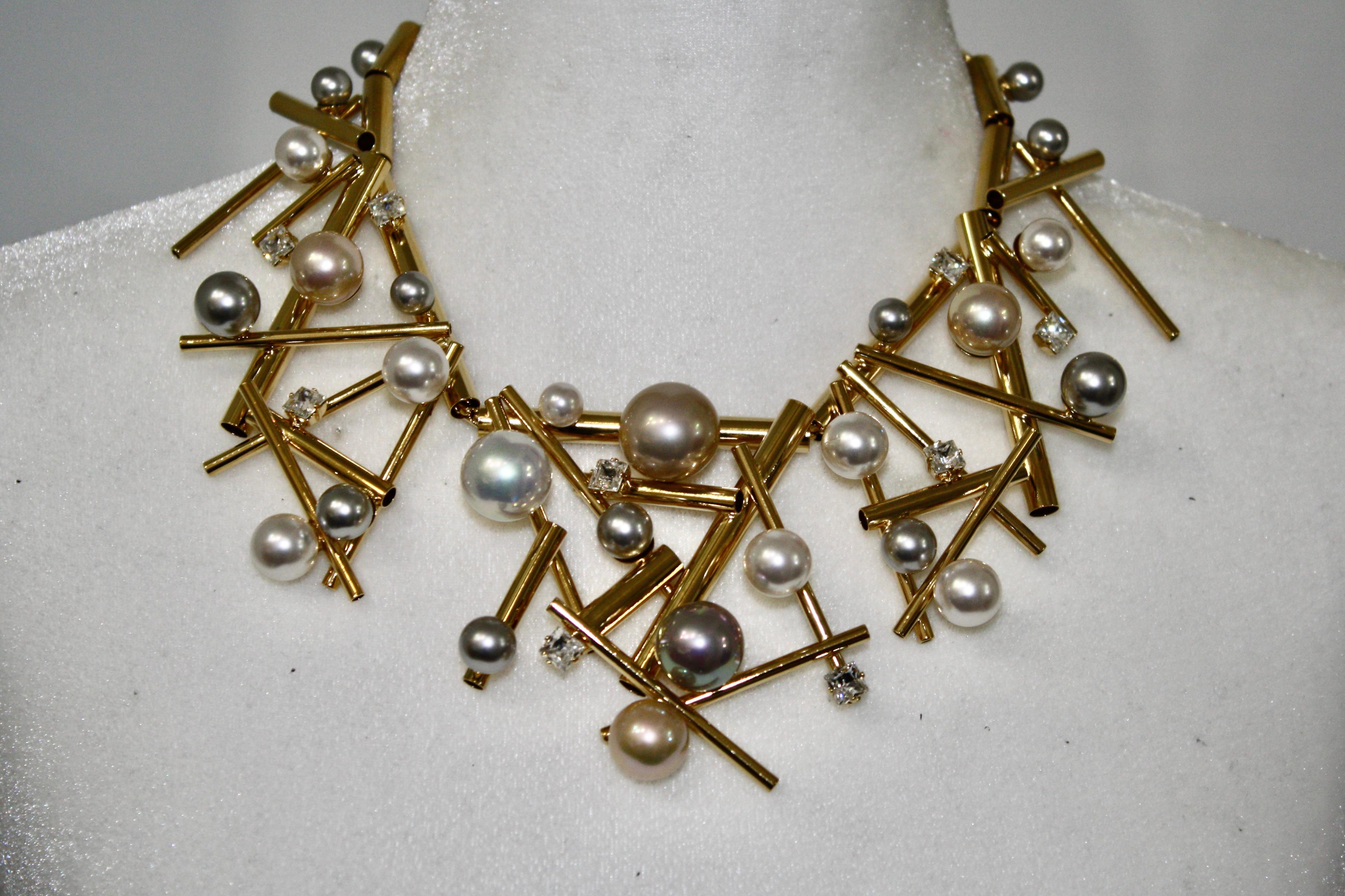 From the Mikado collection, gold metal tubes are threaded through a chain. An intricate design creates a statement necklace. Handmade glass pearls in grey and white.
Chain and hook closure measures 3”.
Signature on the back.