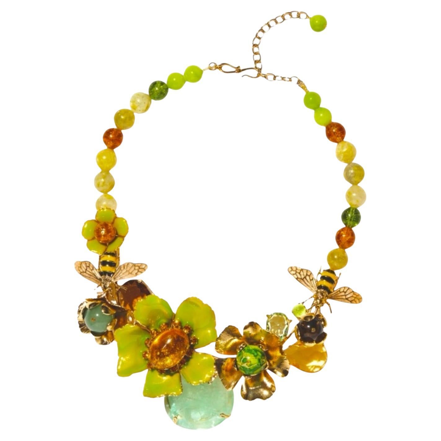 This necklace unfolds a bouquet of lacquered flowers and golden stones like a Bagatelle flowerbed

Finely enameled metal flowers on a 24-karat gold-plated brass structure. Green fluorite and aventurine, faceted brown and honey crystals. Natural