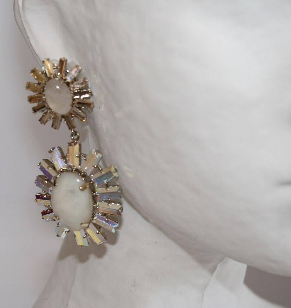 Opaline glass cabochons are surrounded by champagne and clear Swarovski crystals in these drop clip earrings from Philippe Ferrandis.