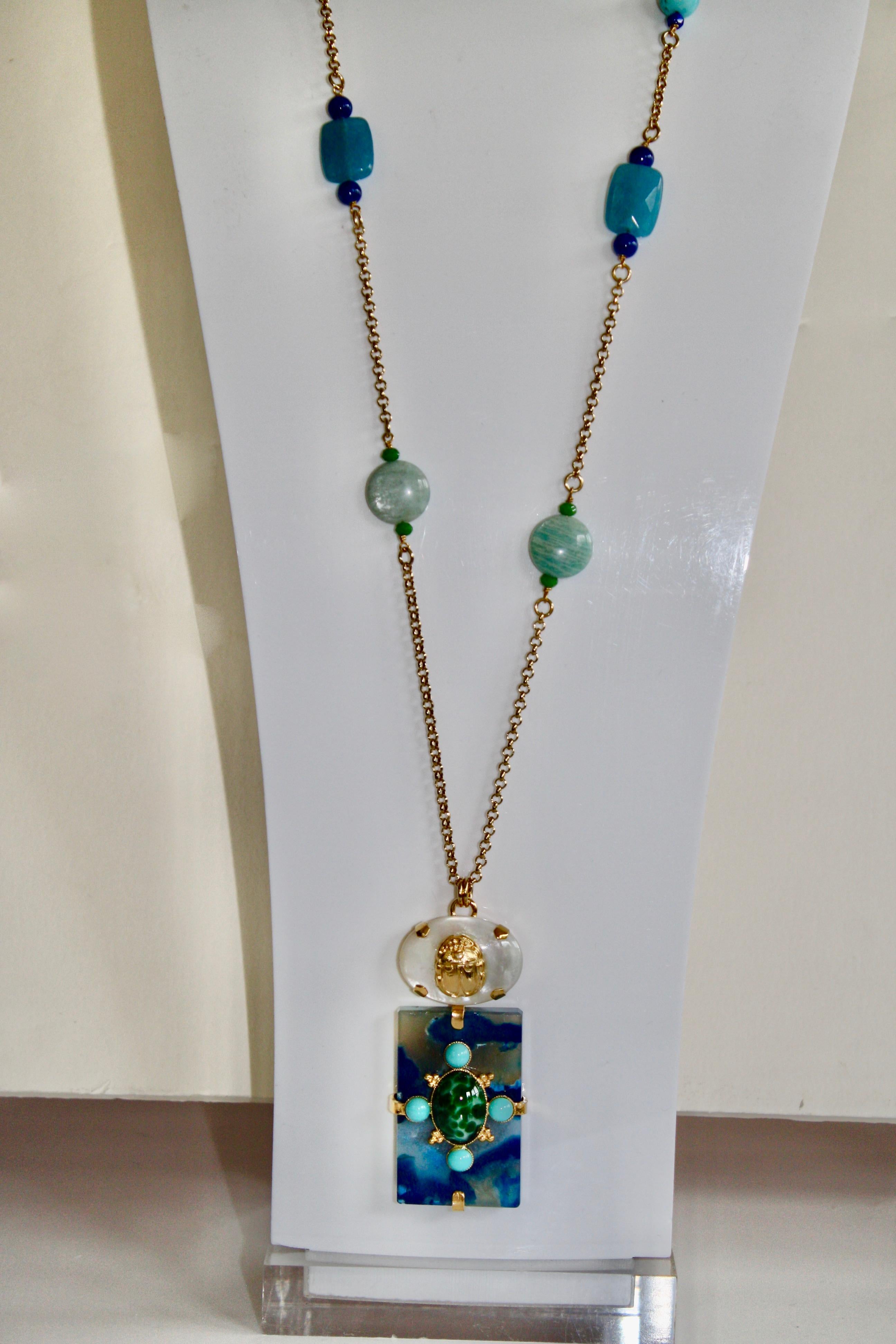 Long chain necklace with turquoise, lapis, and mother of pearl pendant from Philippe Ferrandis. 