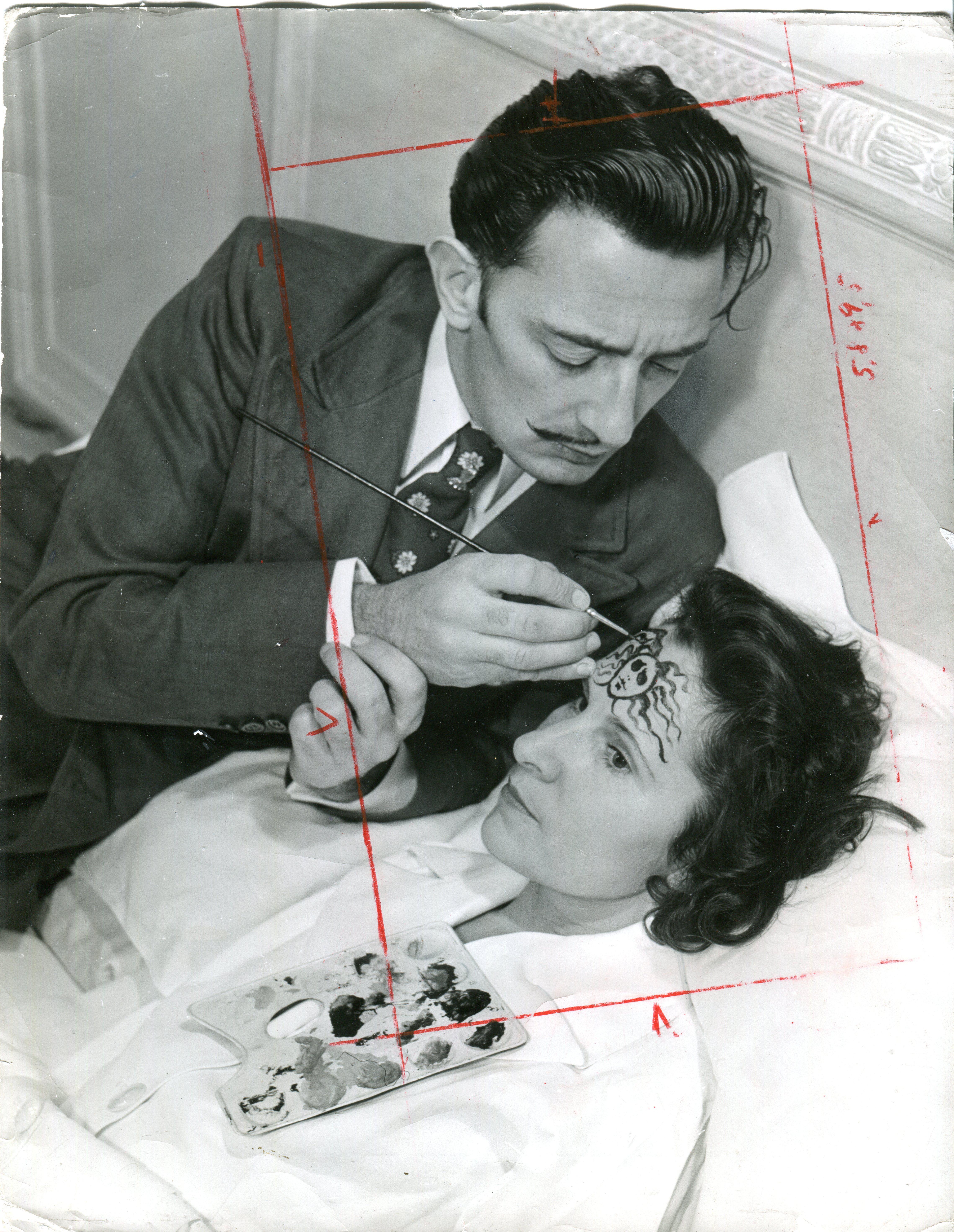 Philippe Halsman Black and White Photograph - Dali is painting medusas head on Galas forehead