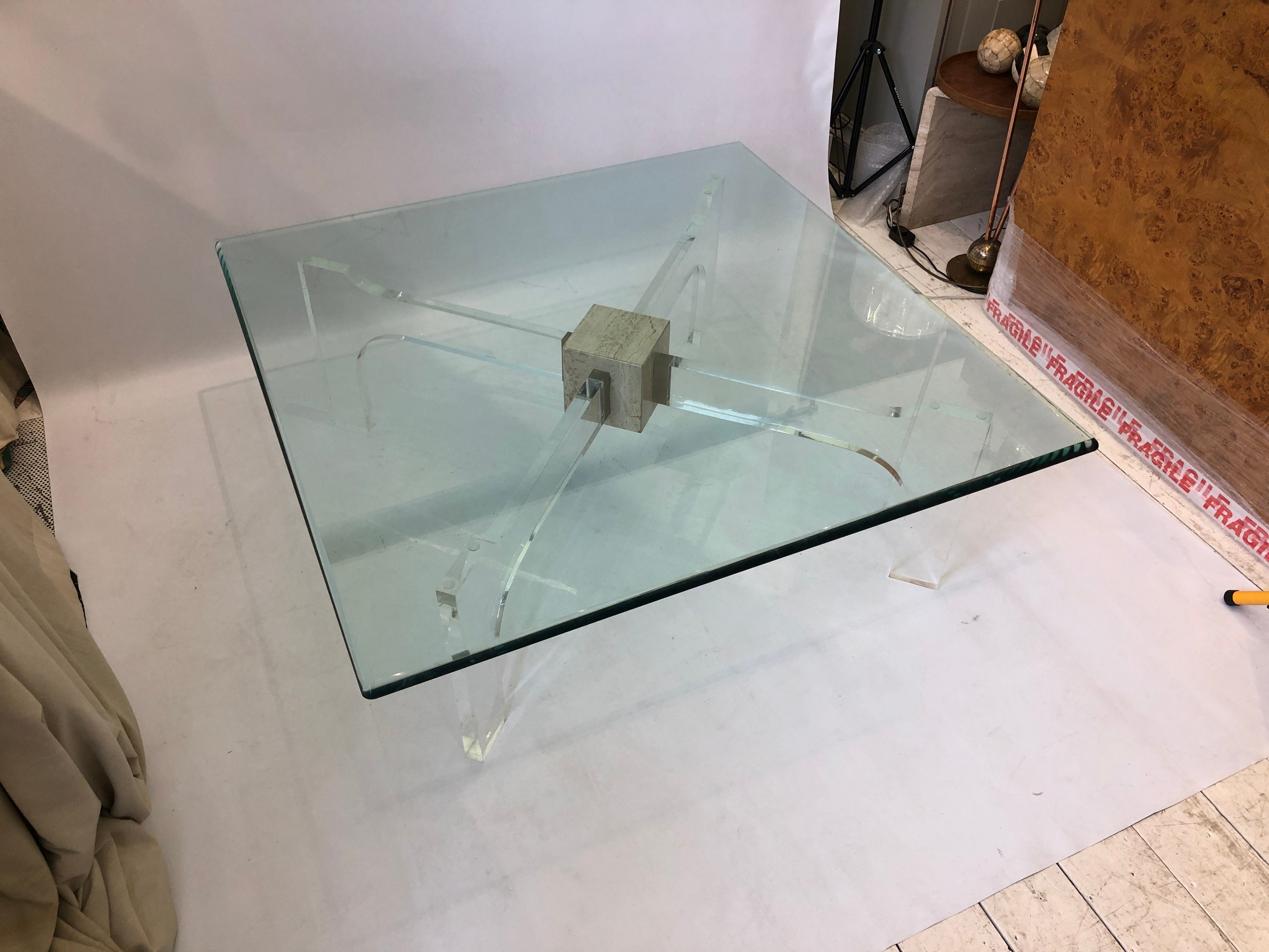 An impressive, large coffee table in the manner of Philippe Jean and imported from France and consisting of a travertine central cube, from which protrudes four clear lucite keys secured by brass fittings. The base fits the glass at an X, creating a