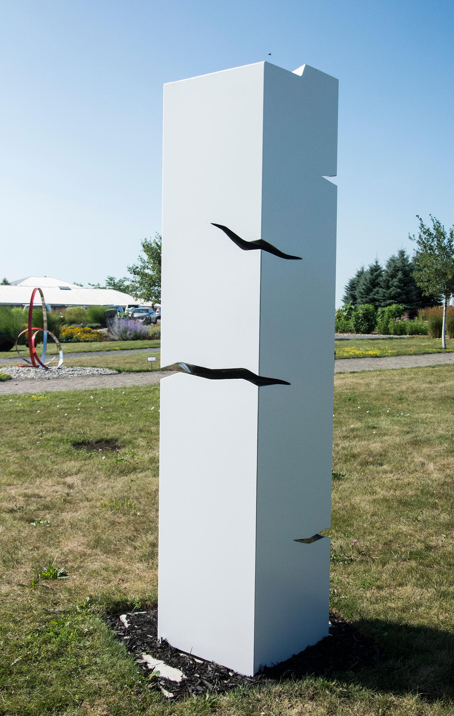 A pillar of stainless steel is coated white in this minimalist outdoor sculpture by Philippe Pallafray. The sculpture is designed with jagged polished cracks in the steel that glint in the sunlight. The artist ascribed meaning to reflected light by
