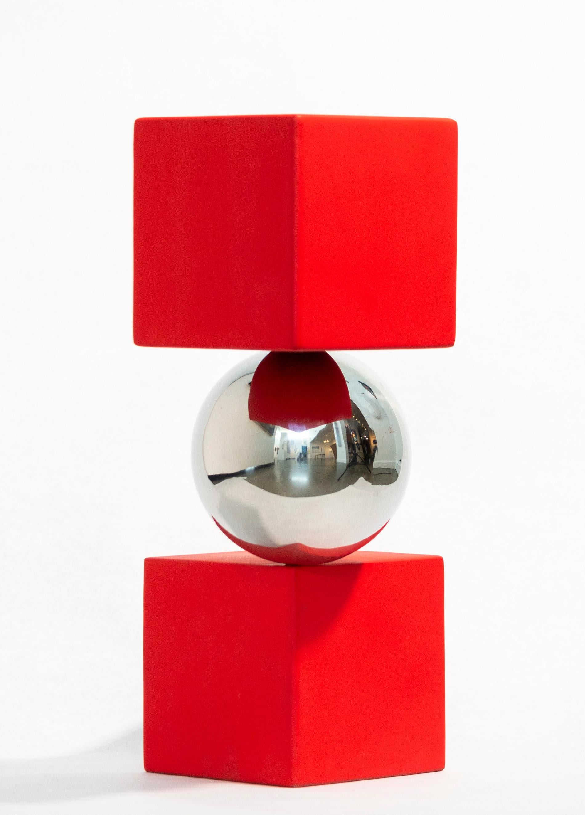 Les sculptures contemporaines spectaculaires de Philippe Pallafray semblent souvent défier les lois de la gravité. Cette imposante pièce minimaliste présente une boule en acier inoxydable hautement poli en équilibre précaire entre deux cubes peints