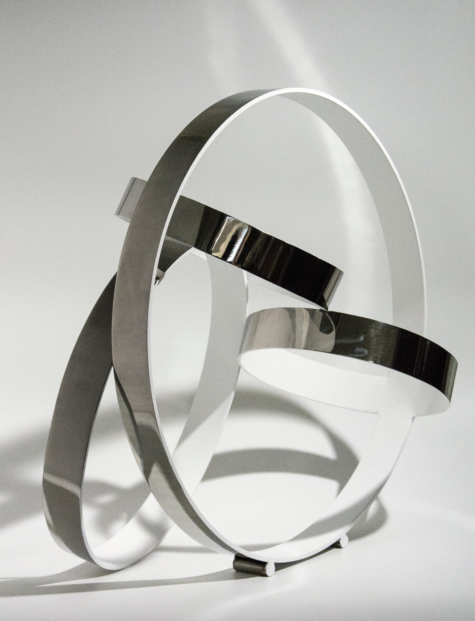 Rings of stainless steel, polished to a high sheen on the exterior and matte white on the interior, intersect at dynamic angles in this elegant sculpture by Philippe Pallafray. This piece is available by commission, please allow 4-5 weeks for