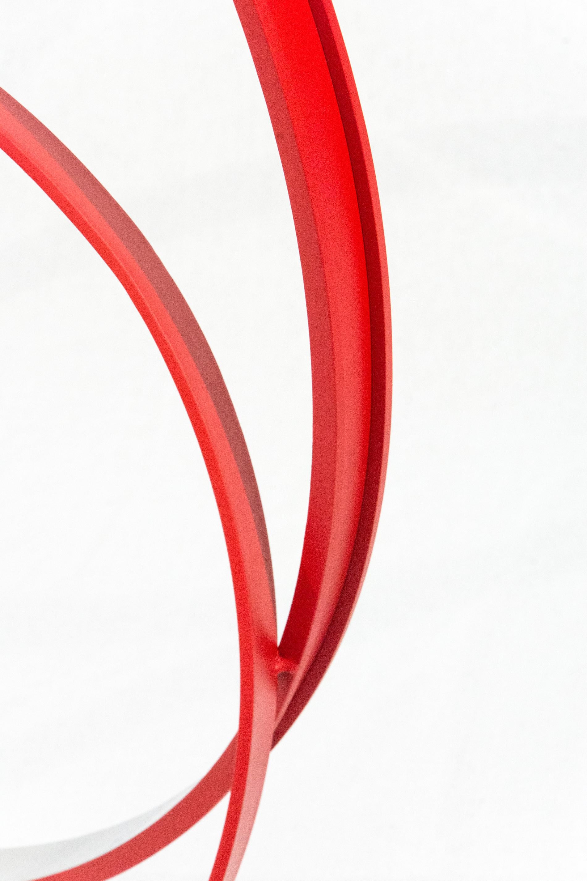 The elegant minimal form of this sculpture is accentuated by its bright poppy red exterior. This is Philippe Pallafray. Hand forged from aluminum, the four rings of various sizes sit inside and opposite one large ring. The interior of each ring is